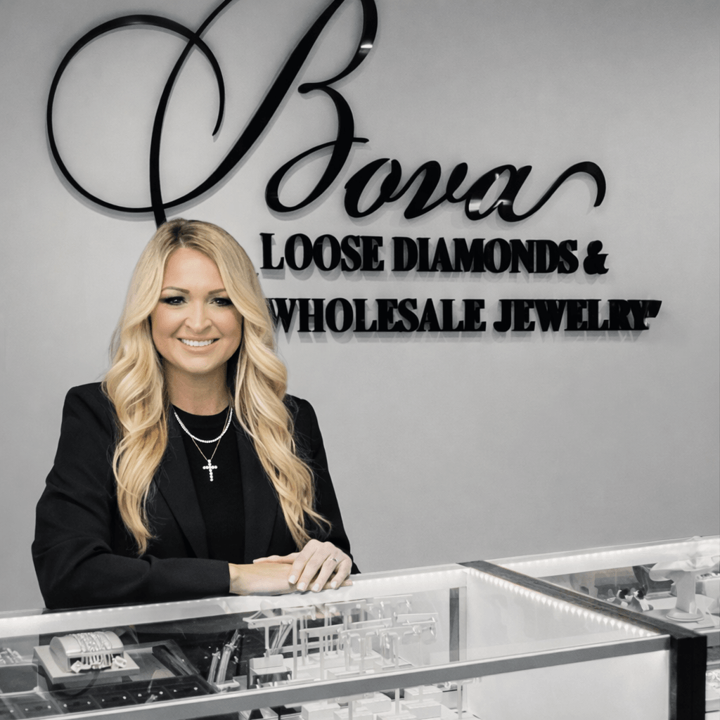 Woman with long blonde hair smiling behind jewelry display case in jewelry store.