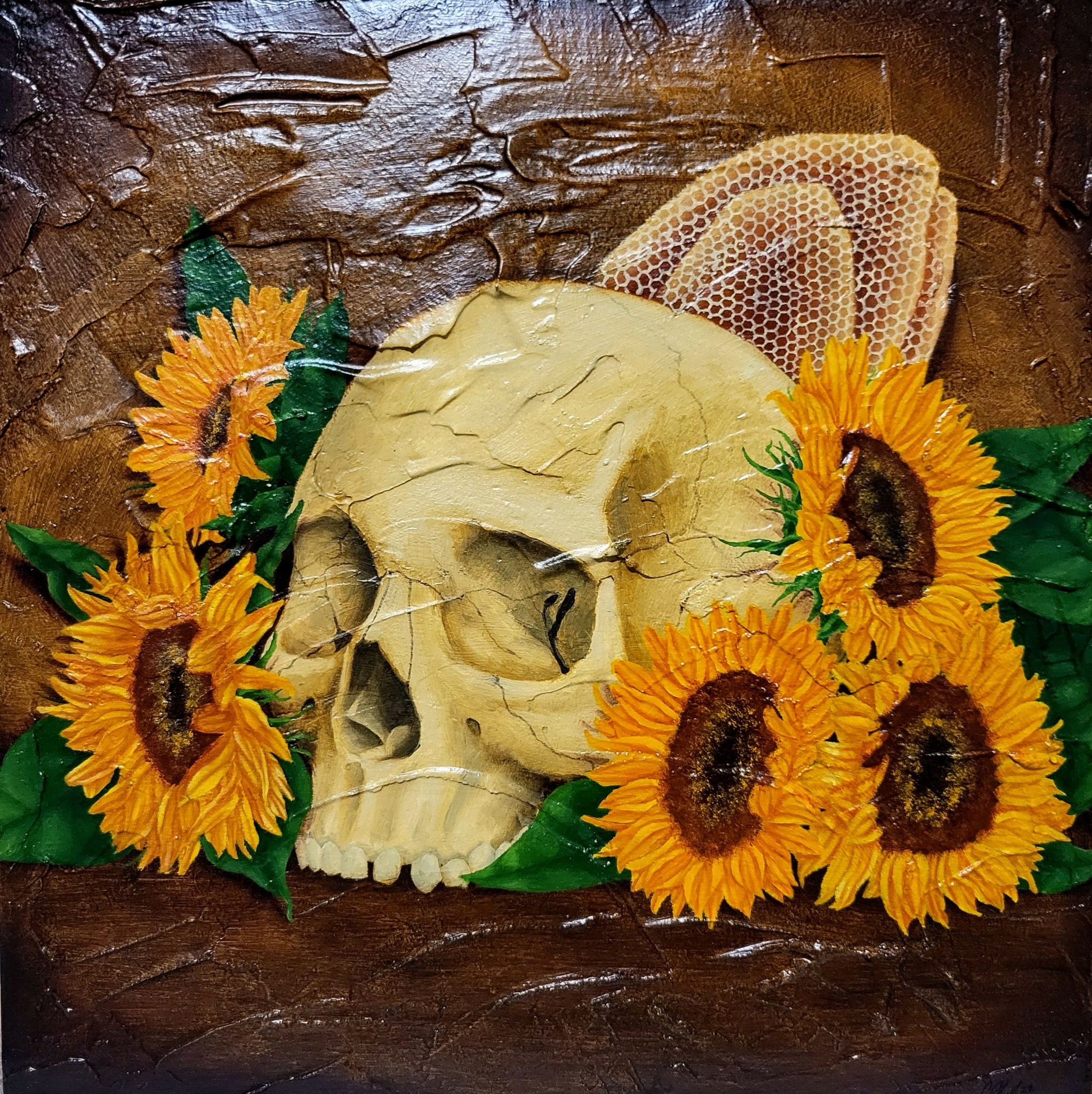 Skull surrounded by sunflowers and honeycomb on a wooden surface.