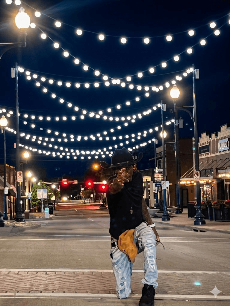 Person standing on a street at night under hanging string lights, with buildings and streetlights in the background.