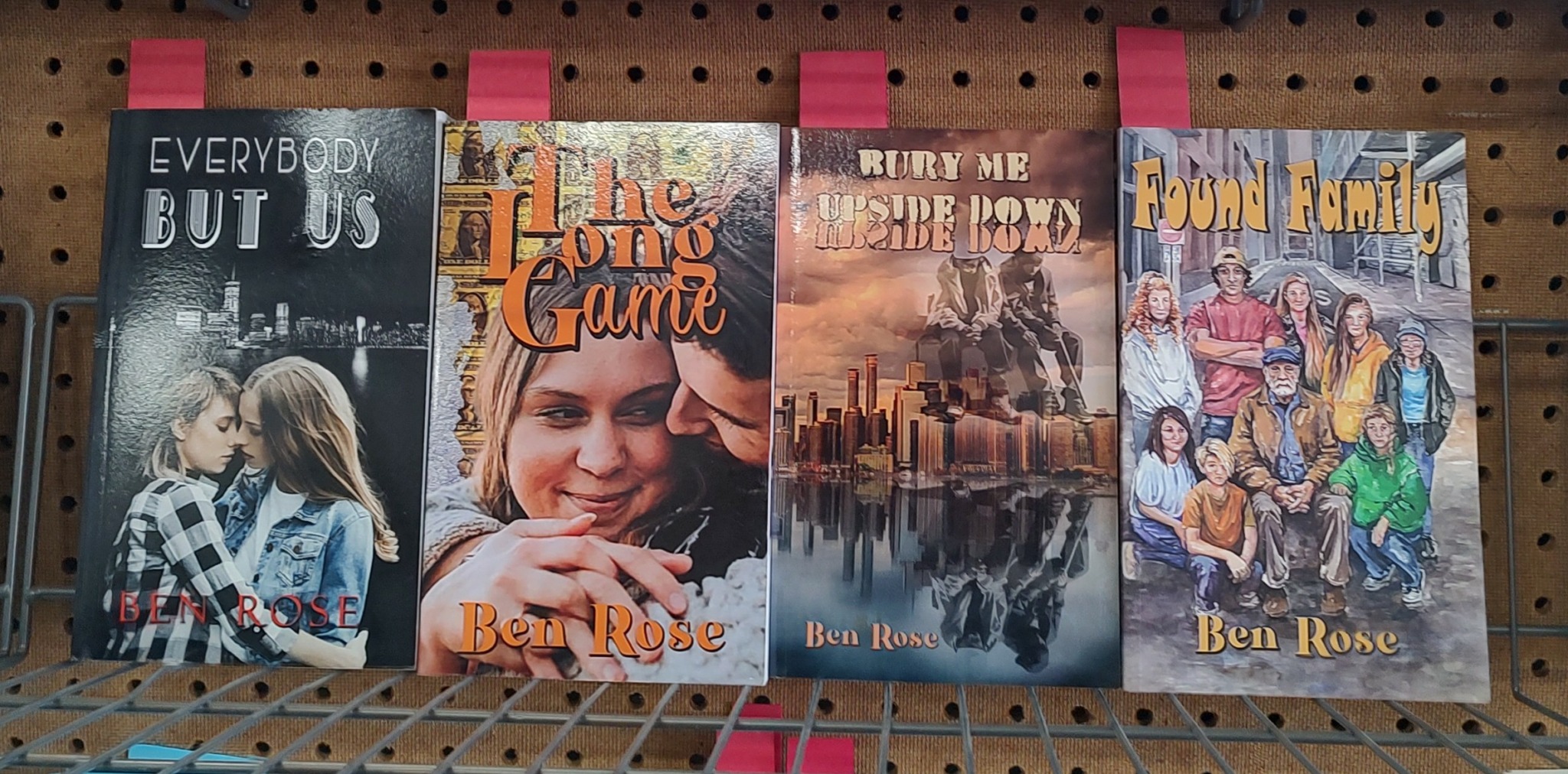 Four books on a shelf with colorful covers, featuring people and scenes, arranged from left to right.
