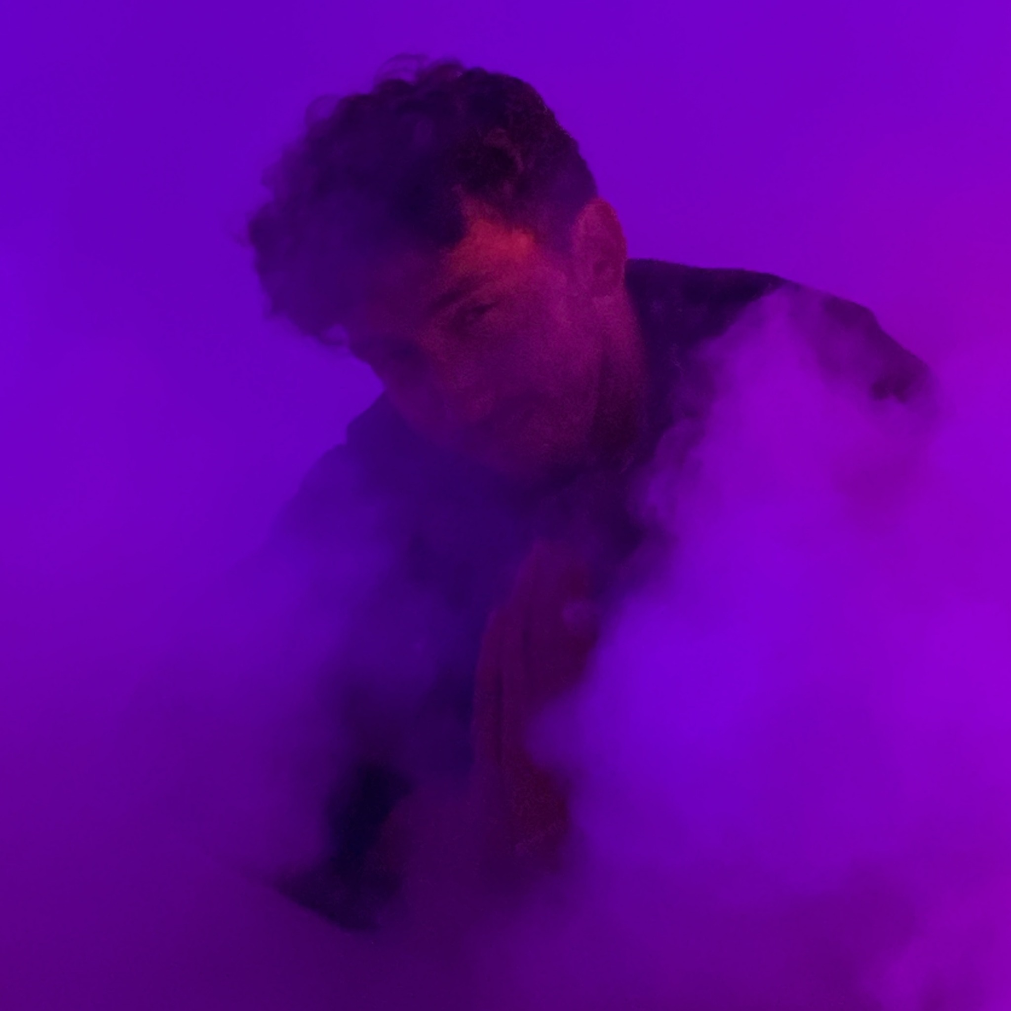Person with curly hair in purple lighting, surrounded by fog or smoke, with hands pressed together.