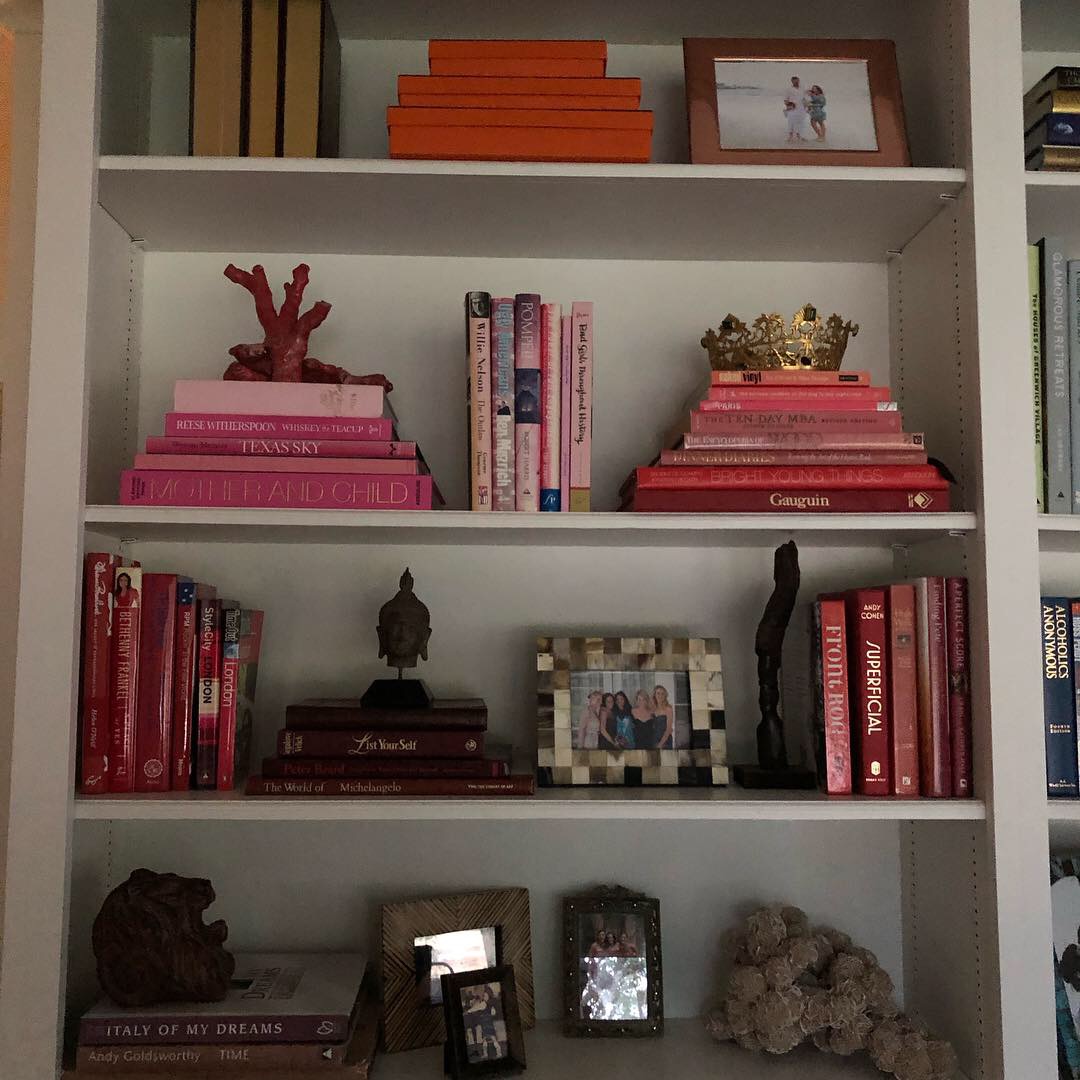 Bookshelf with colorful books, decorative items, and framed photos on four shelves.