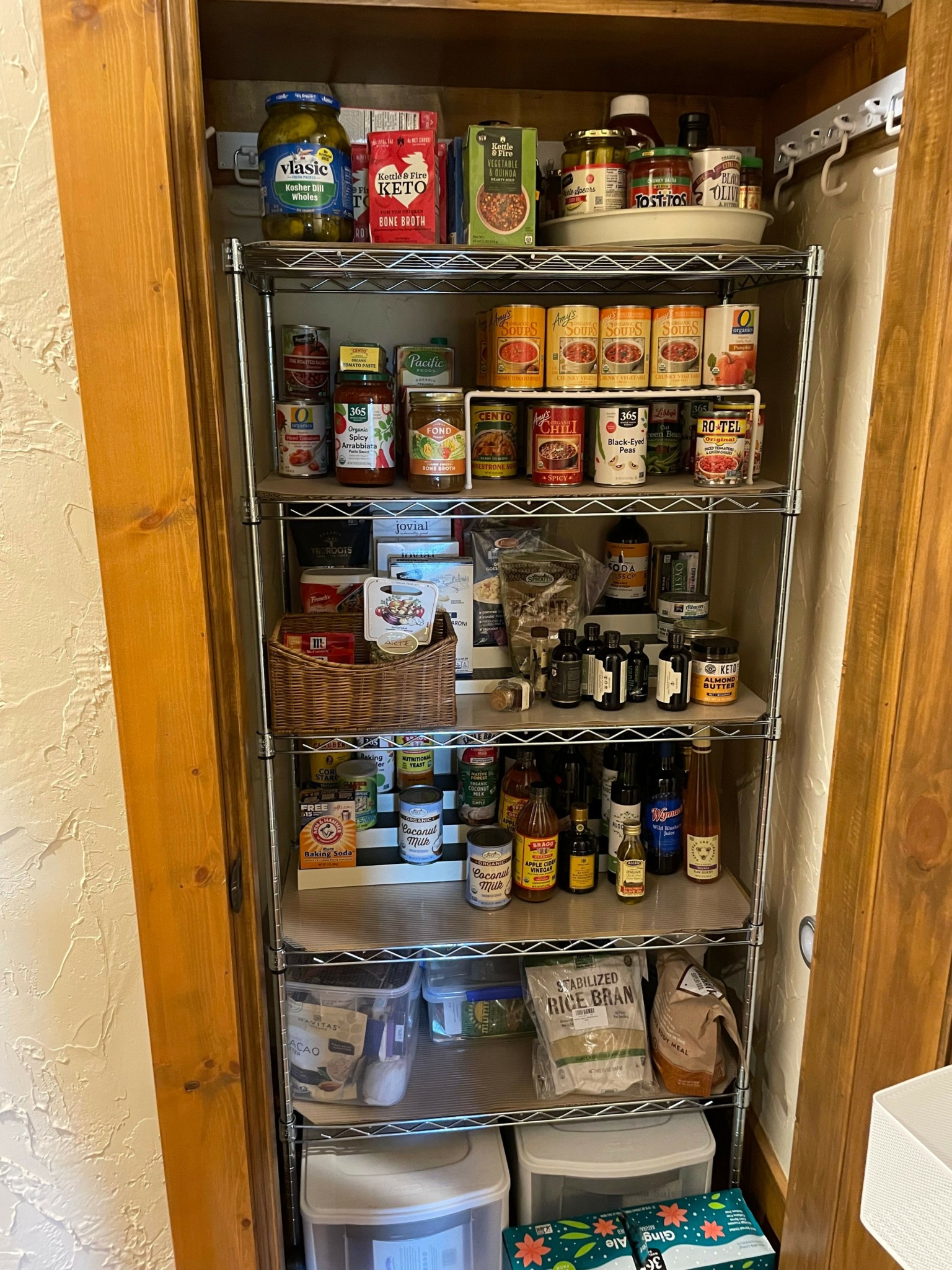 Pantry with shelves holding canned goods, spices, bottles, and storage containers, organized in a narrow space.