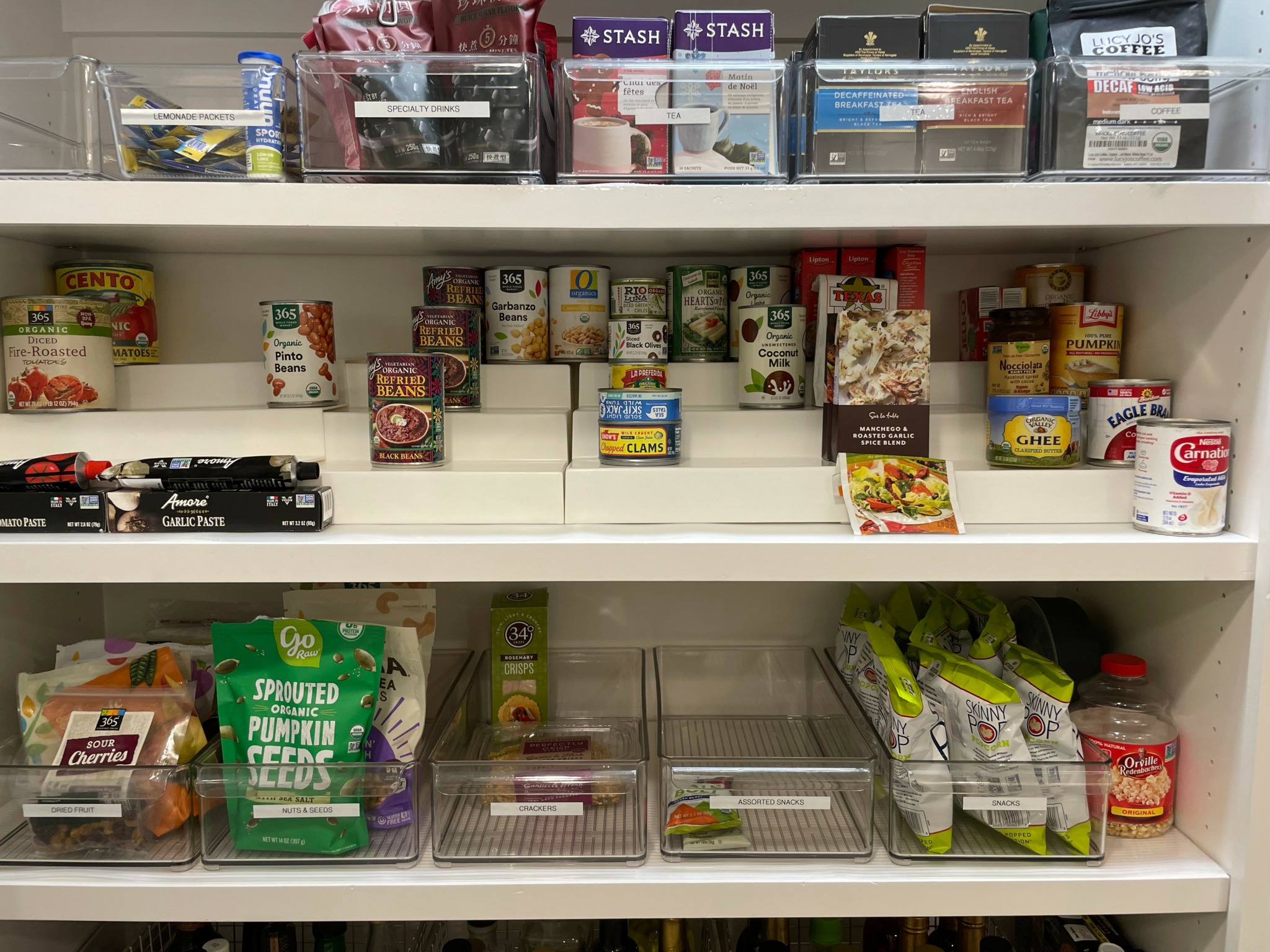 Shelves with canned goods, boxed food, and plastic containers in a pantry.
