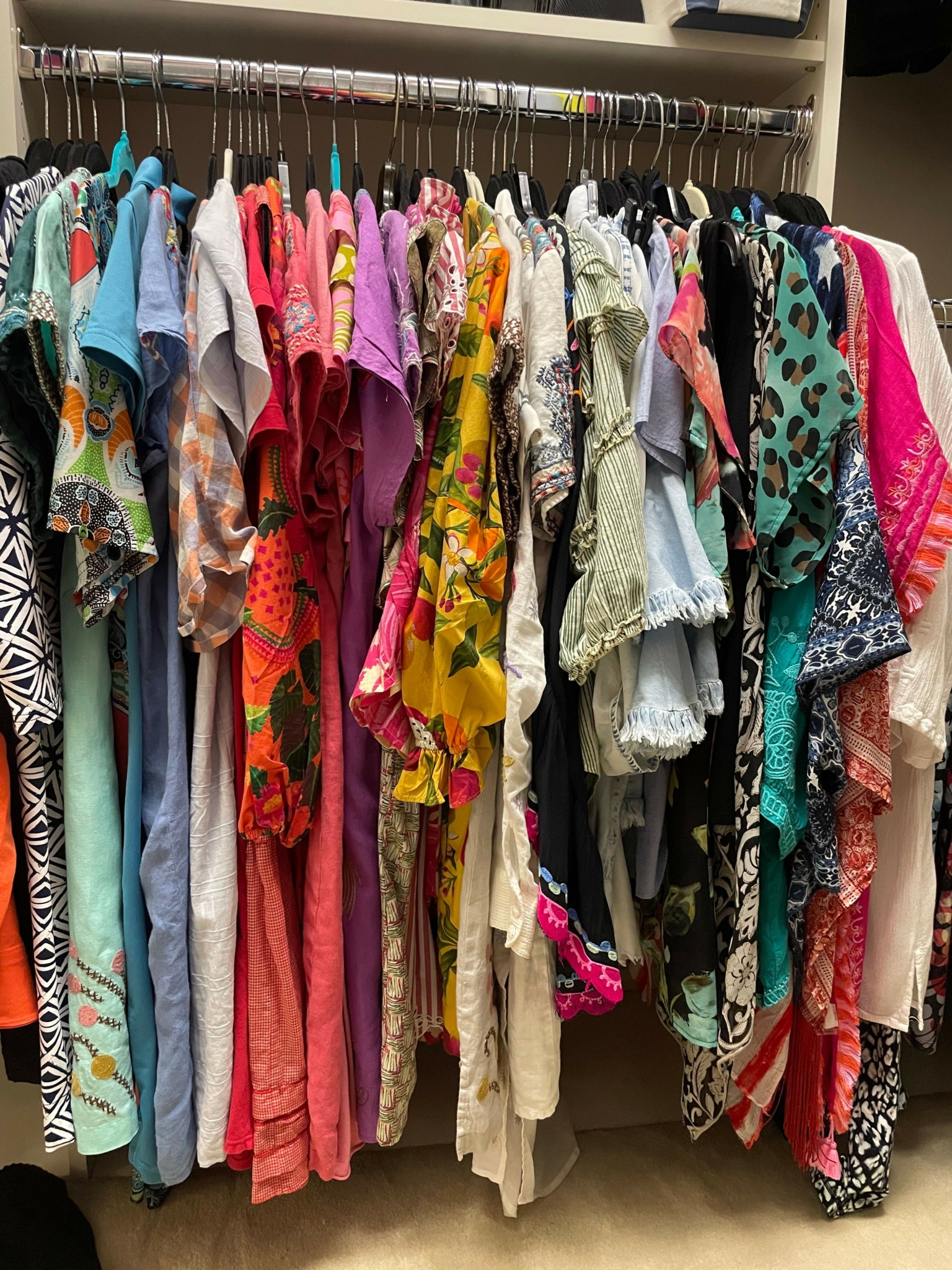 Stack of folded colorful fabrics and clothing items in a closet, with various patterns and textures.