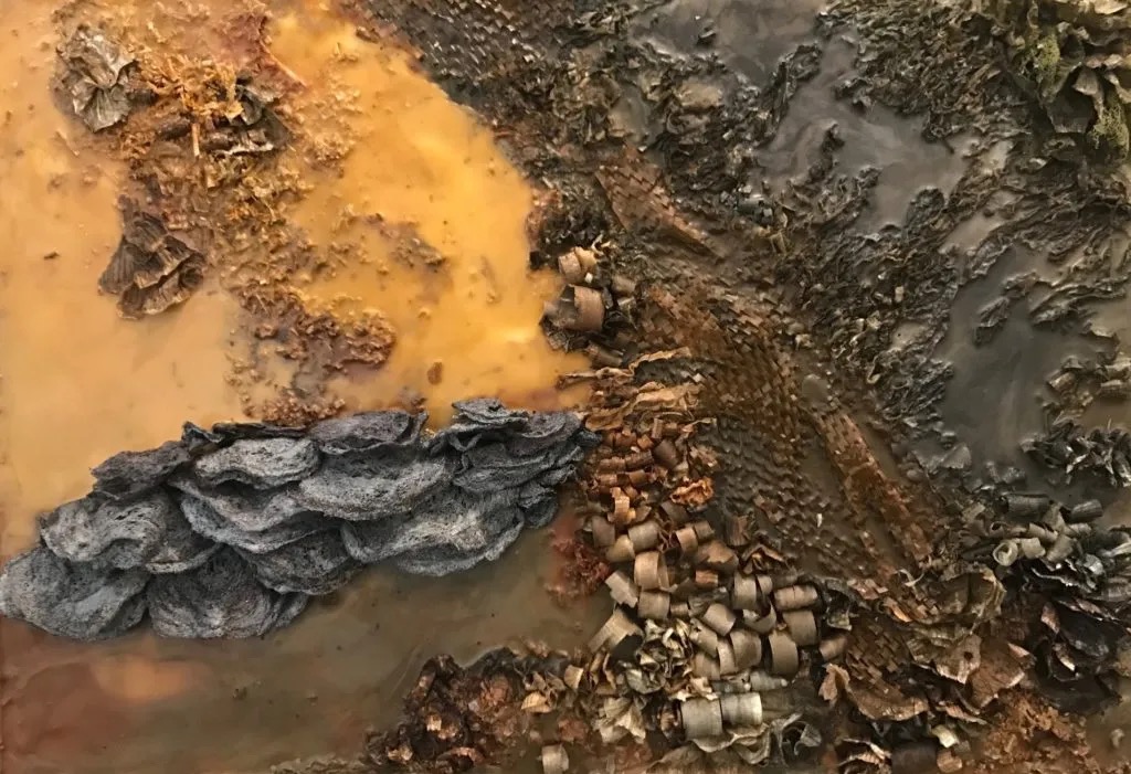 Close-up of textured rocks, soil, and small objects on uneven ground, with various colors and rough surfaces.
