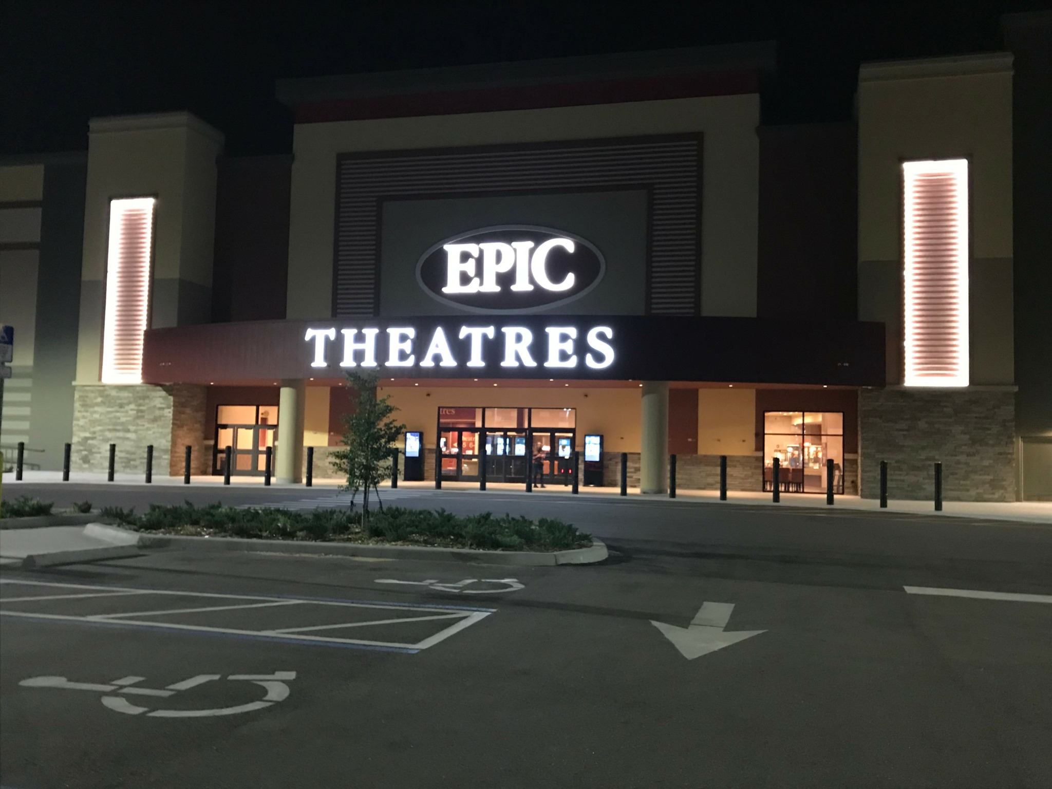 EPIC THEATRES building at night with illuminated sign, entrance, and parking lot in foreground.