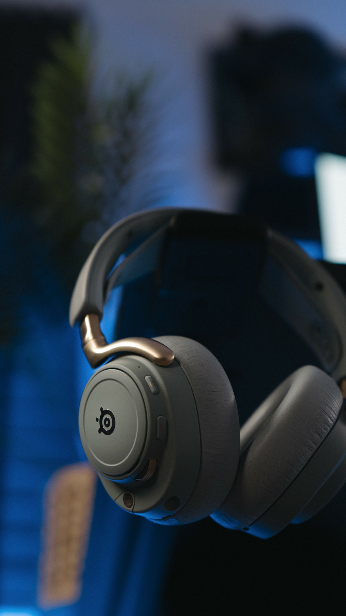 Over-ear headphones with a circular logo on the ear cup, set against a blurred background.