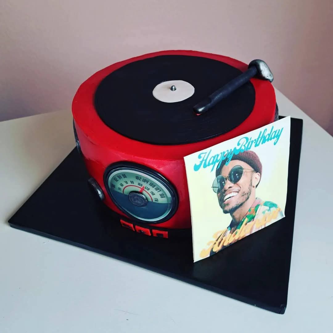 Cake designed as a turntable with a photo of a smiling person wearing sunglasses, a birthday message, and a record player on top.