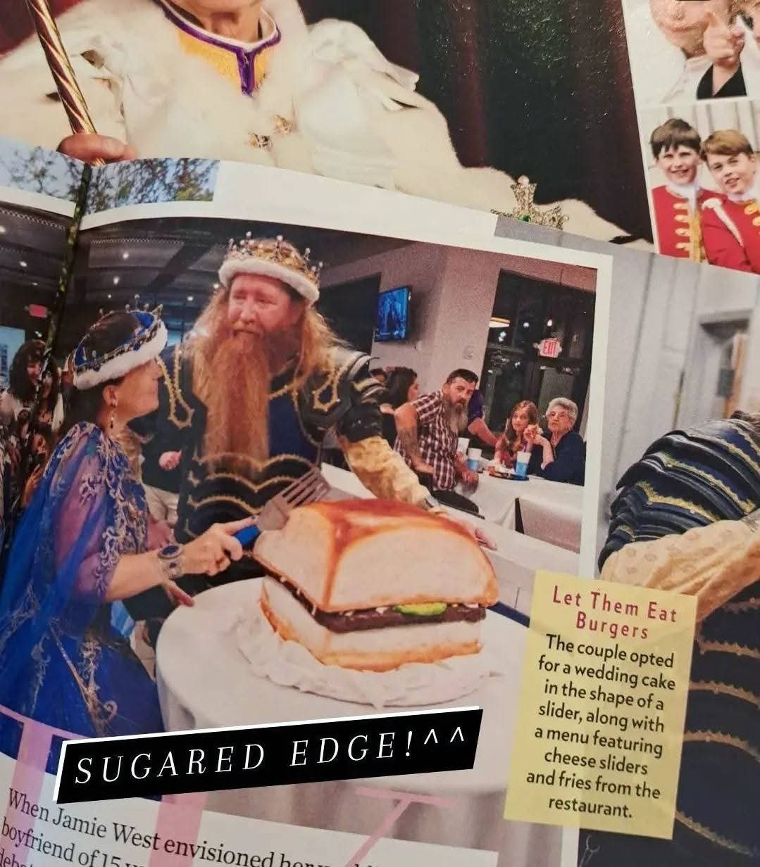 Person with long beard and crown serving a large burger to a child in a festive setting, with people in the background.