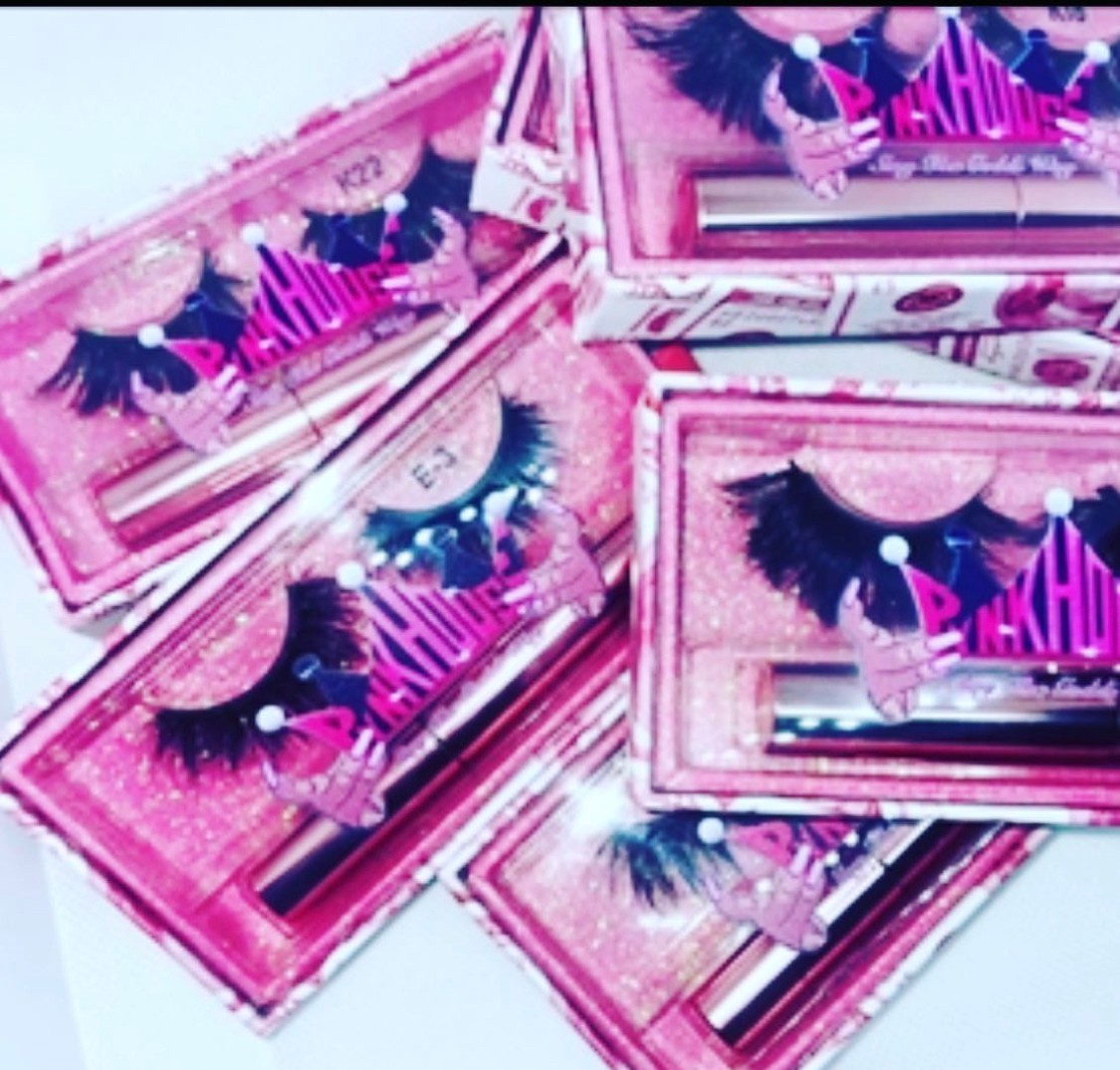 Multiple pink boxes of false eyelashes arranged in a scattered pattern, with some boxes overlapping each other.