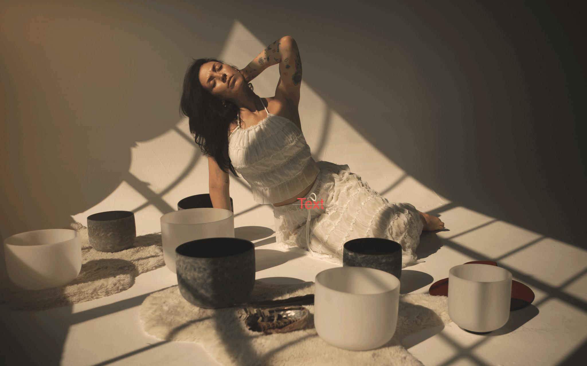Woman sitting on a table with bowls and dishes, shadow cast on the wall, in a dimly lit room.