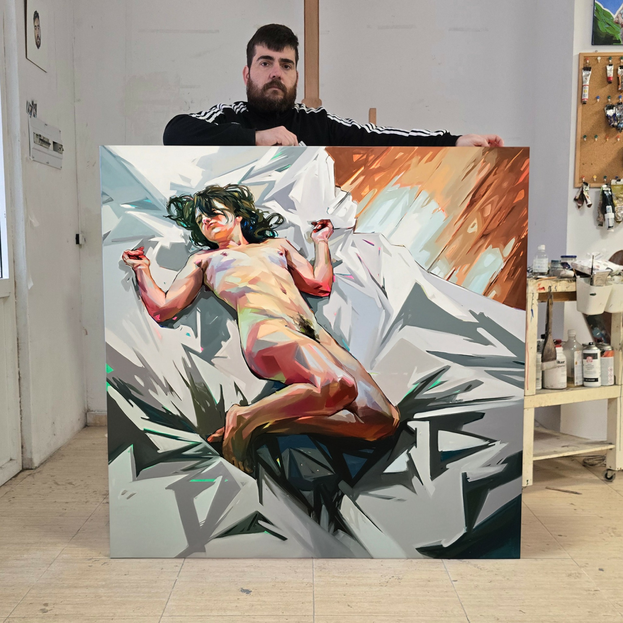 Man holding a large colorful painting of a reclining woman with dark hair, lying on a bed or surface.