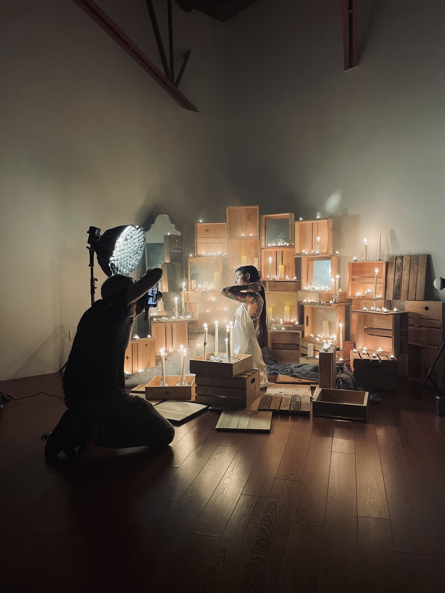 Two children interact with illuminated objects in a dark room with stacked boxes and wooden furniture, creating a cozy scene.