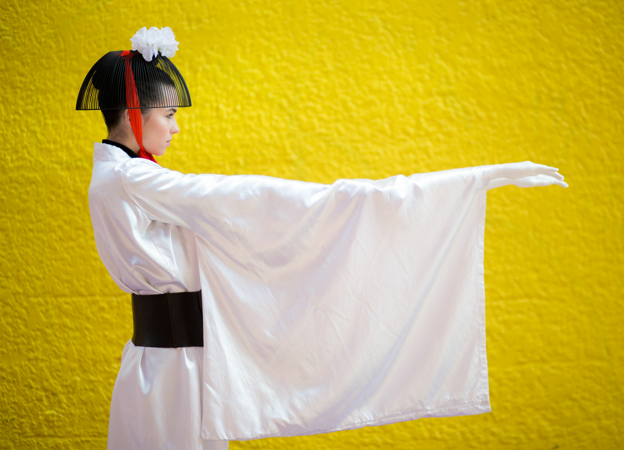 Child in traditional costume with outstretched arm against yellow background.