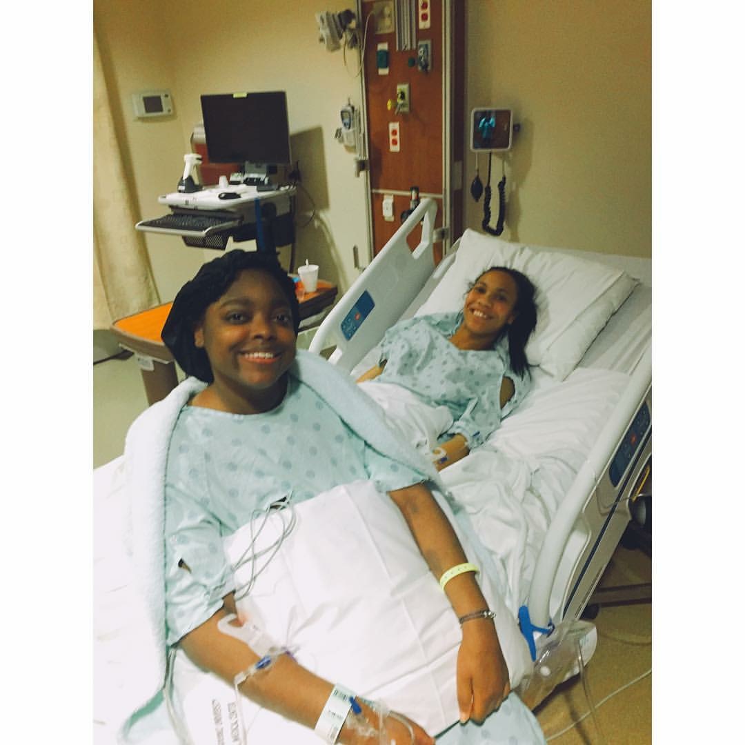 Two women in hospital beds, one smiling at the camera, the other lying down, in a hospital room with medical equipment.