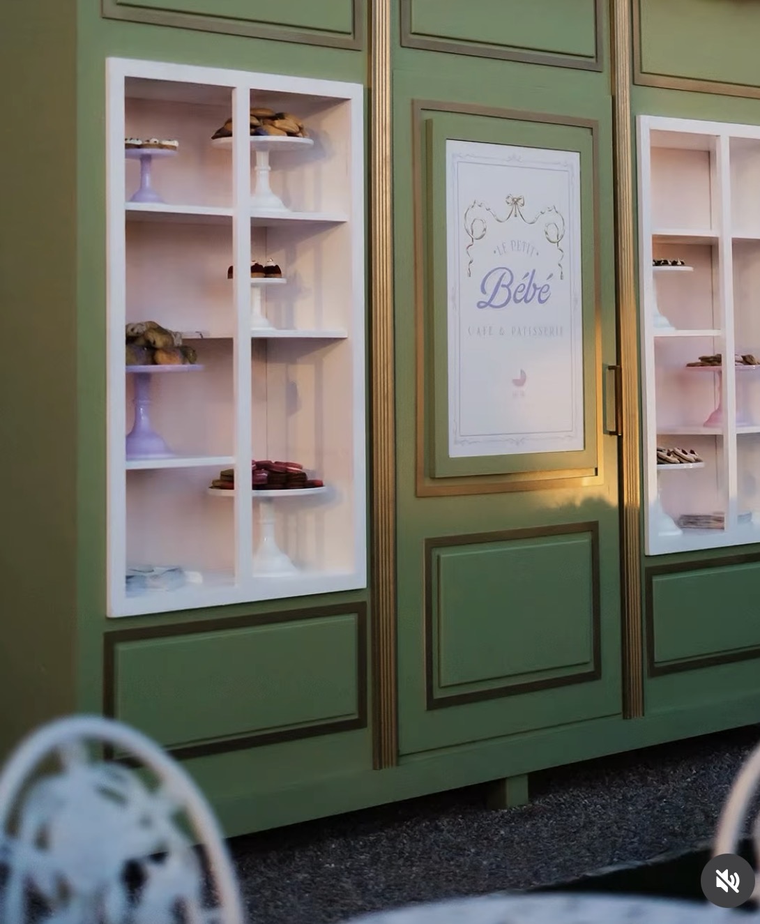 Green display cabinet with glass doors showing shelves of small items, and a sign with the word 'Bébé' in the center.