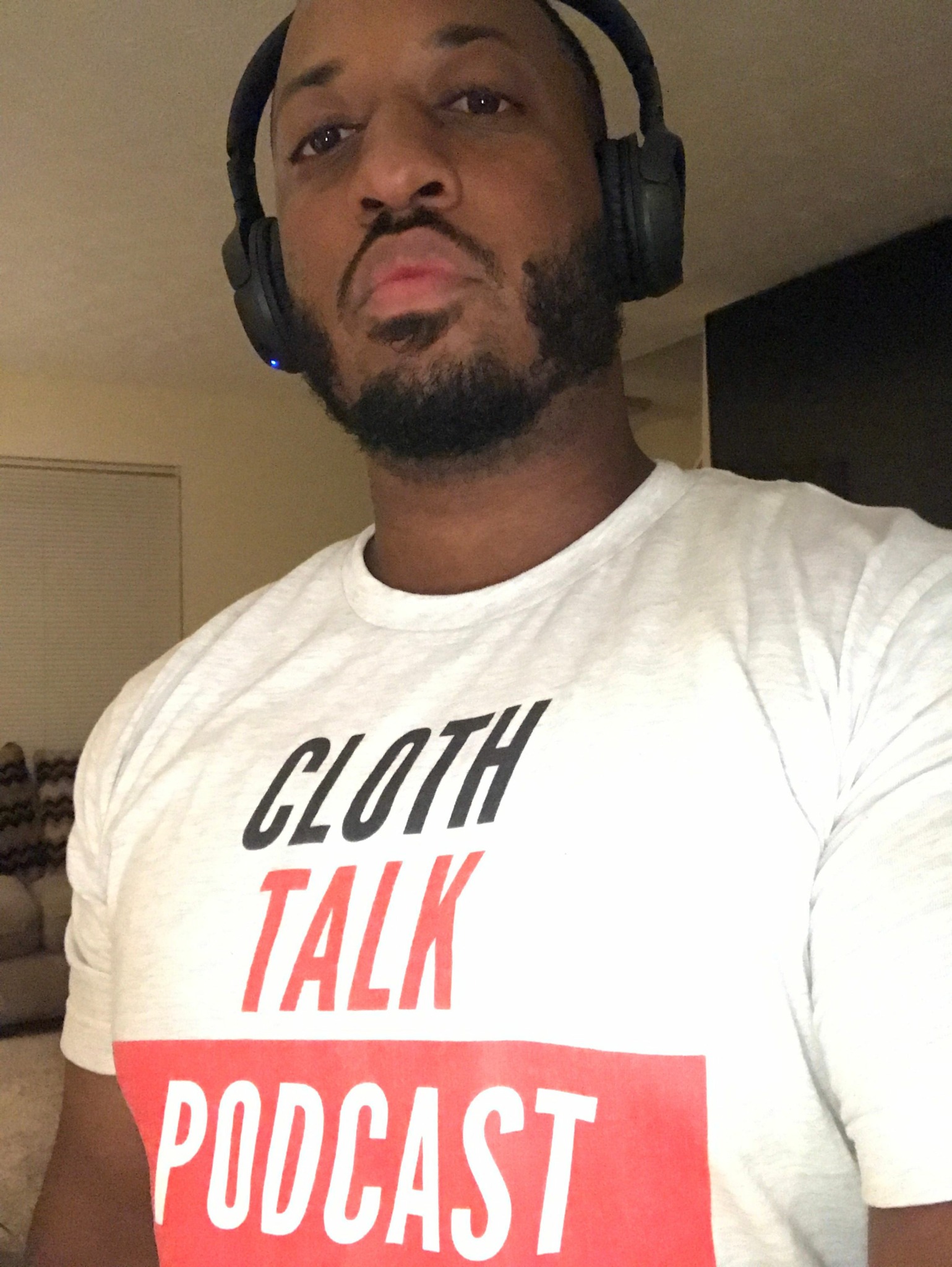 Person wearing headphones and a white T-shirt with red and black text, lying down sideways.