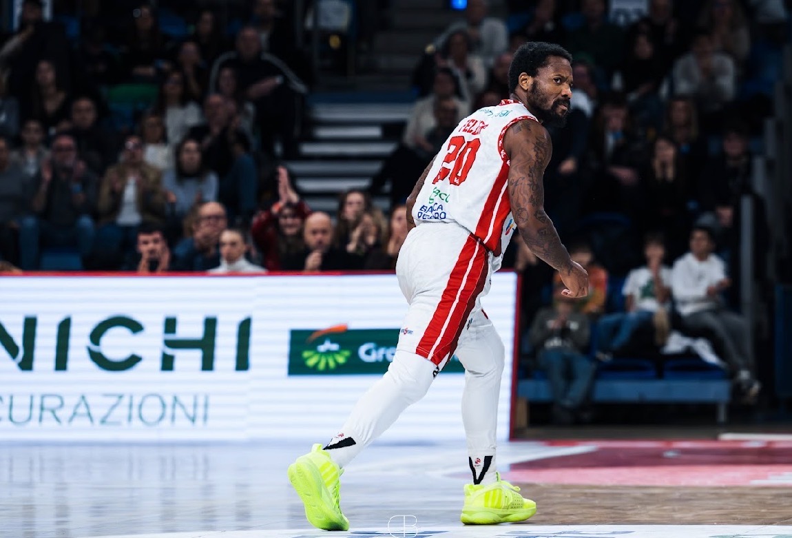 Basketball player in white uniform with red accents, number 20, on court with audience in background.