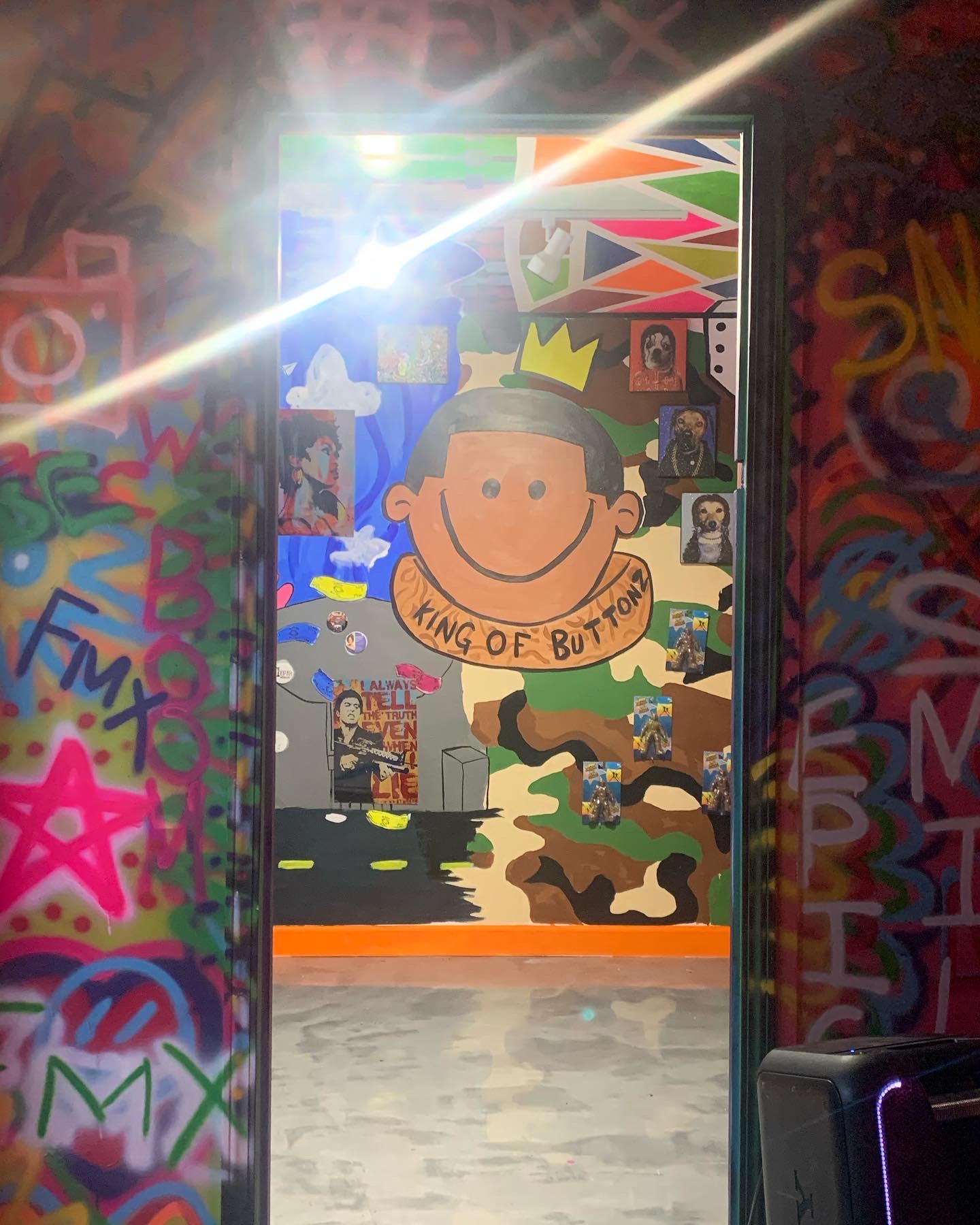 Colorful graffiti-covered walls with a doorway leading to a mural of a smiling cartoon boy wearing a crown, with a banner reading 'KING OF BUT'.