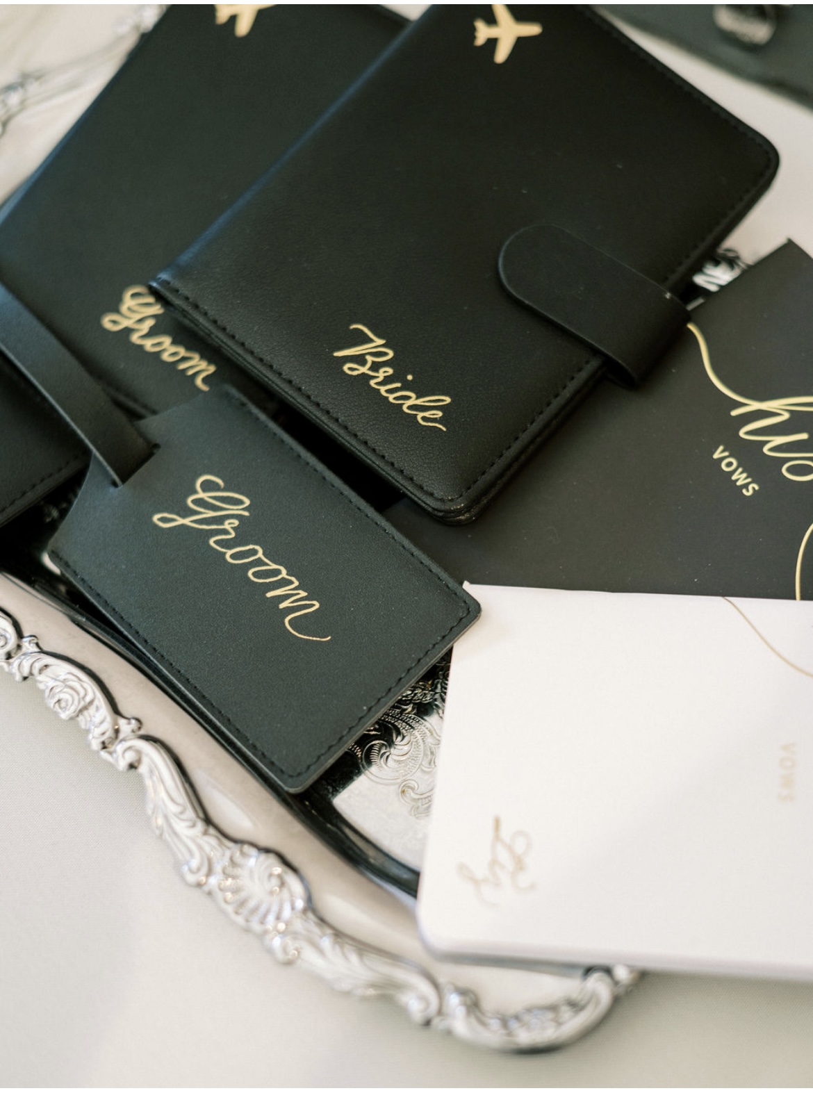 Black wedding planner with gold lettering for bride and groom, surrounded by decorative items.