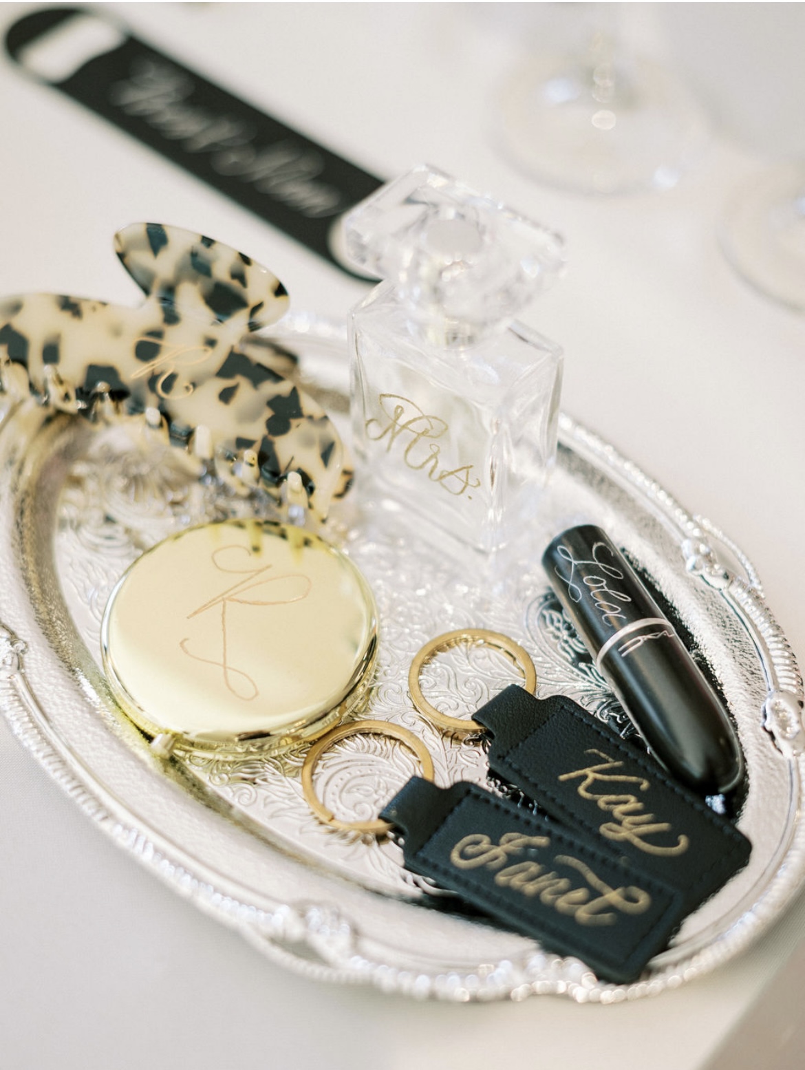 Tray with perfume, keys, lipstick, and accessories on a white surface.
