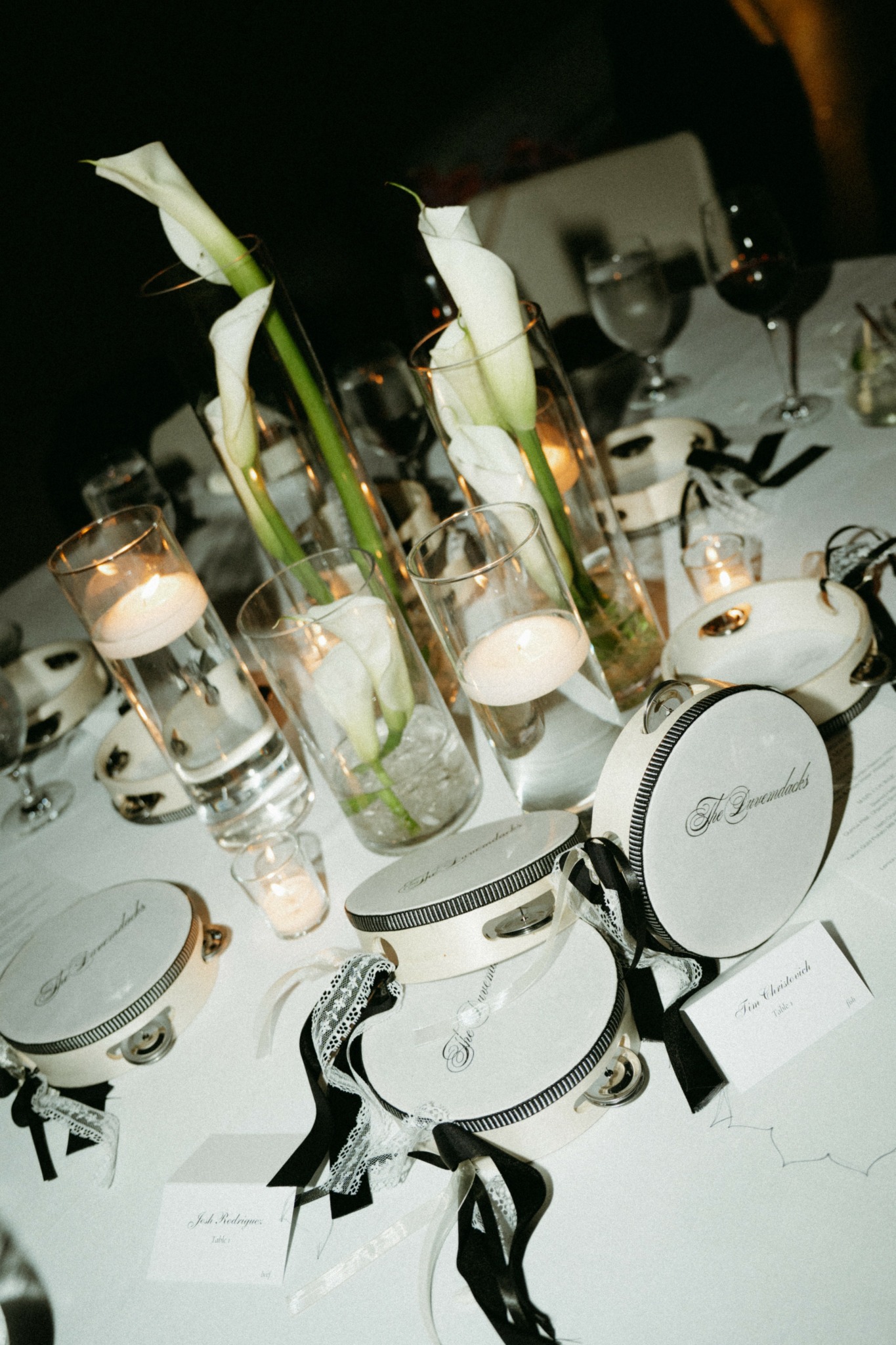 Elegant table setting with white flowers, candles, wine glasses, and black ribbon decorations.