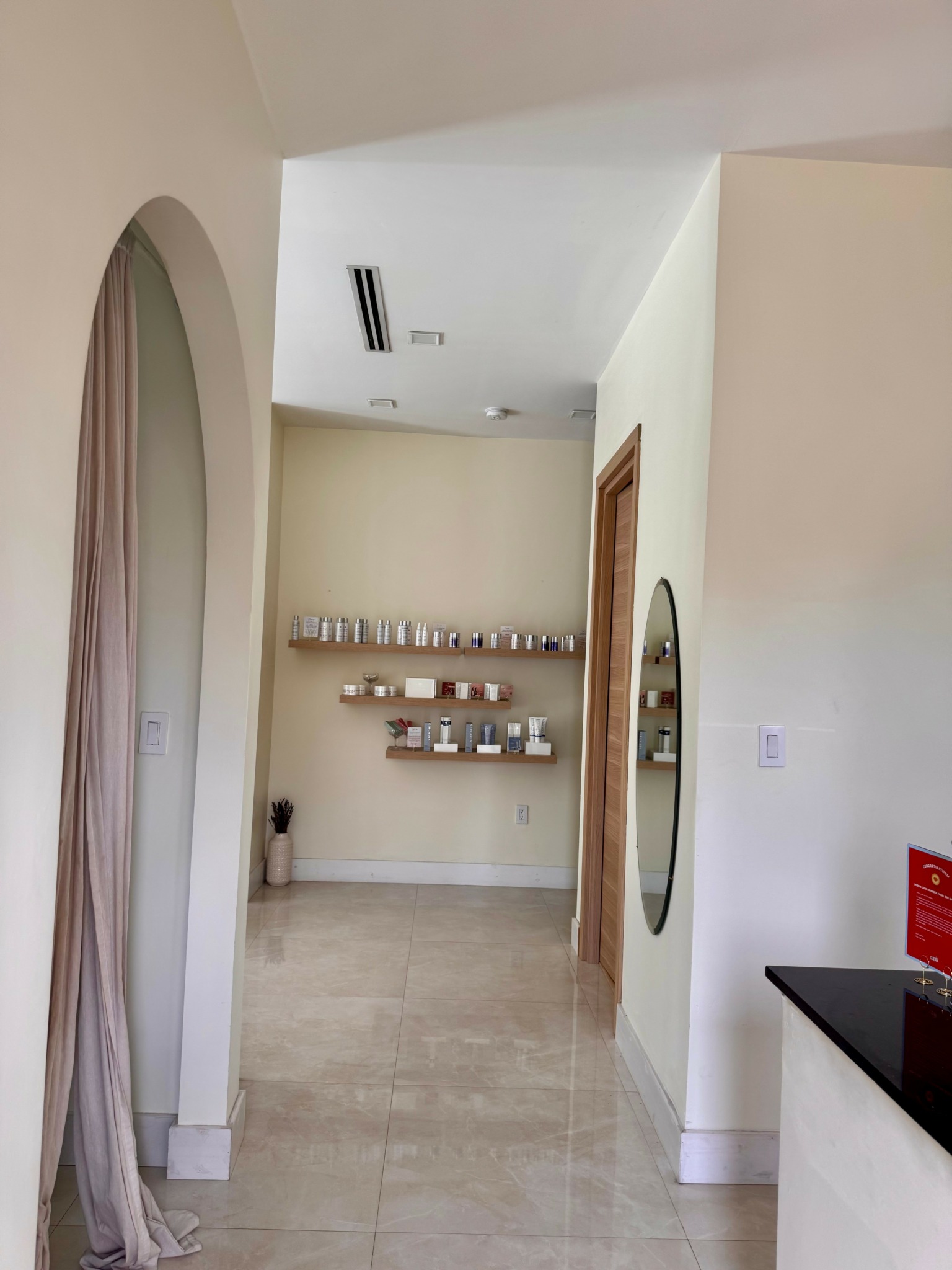 Interior view of a room with shelves on the wall, an arched doorway, and a mirror on the right wall.