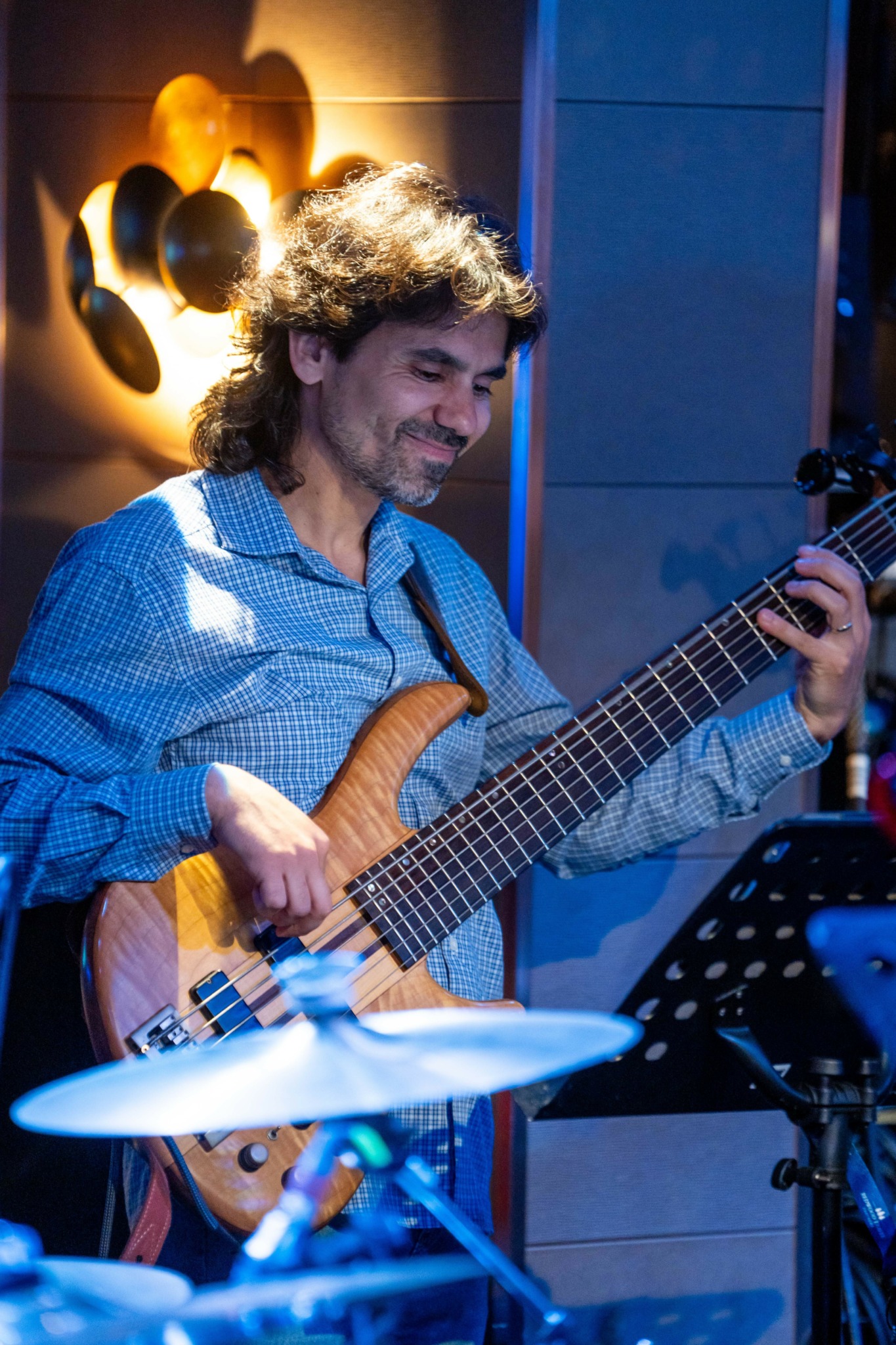 Man playing an electric guitar in a music studio with wall decorations and music equipment.