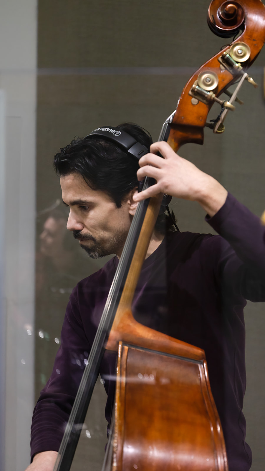 Man playing a double bass, focusing on the instrument and his hand on the strings.