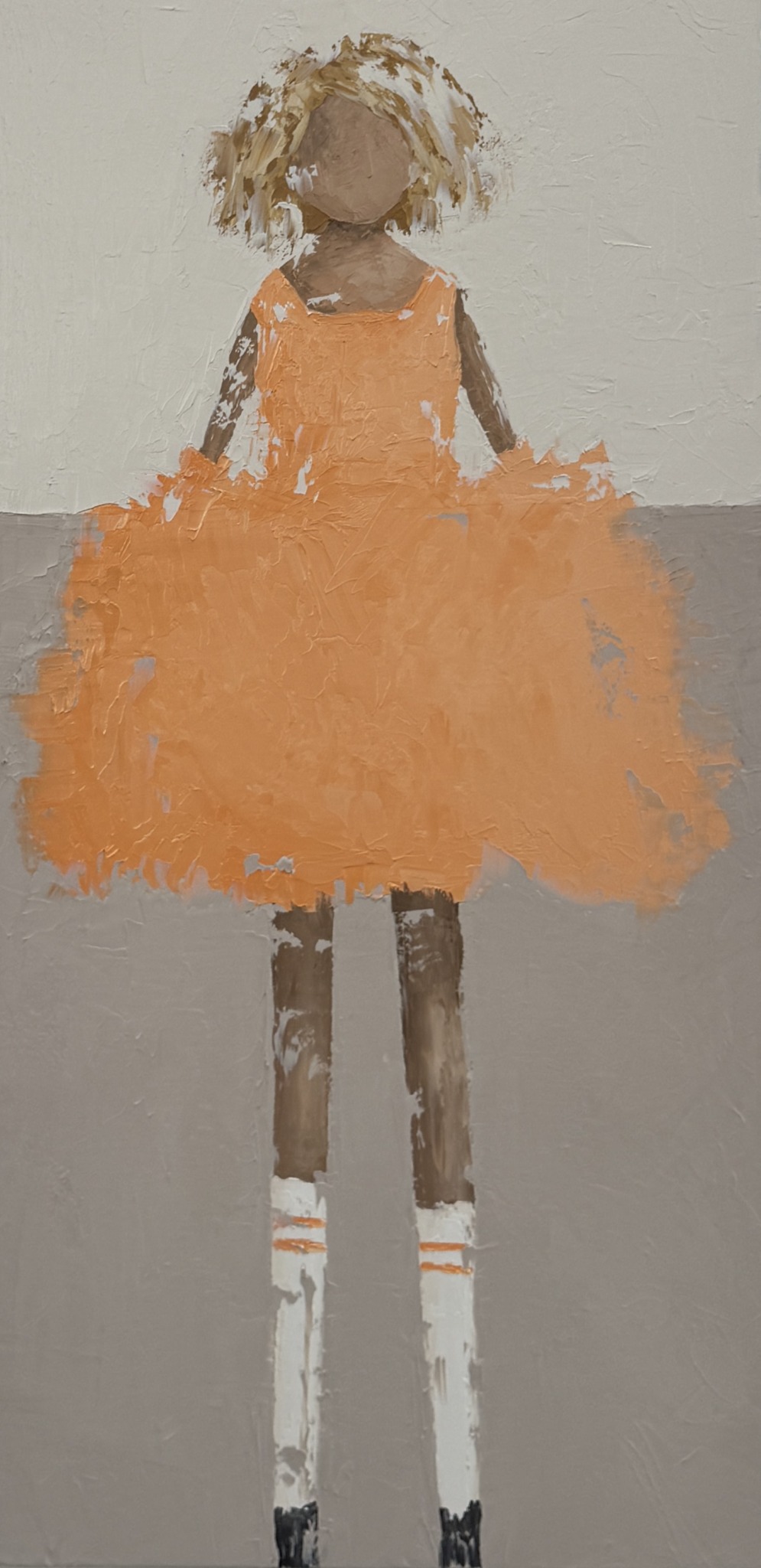 Child with curly hair wearing an orange dress and white socks, standing against a plain background.