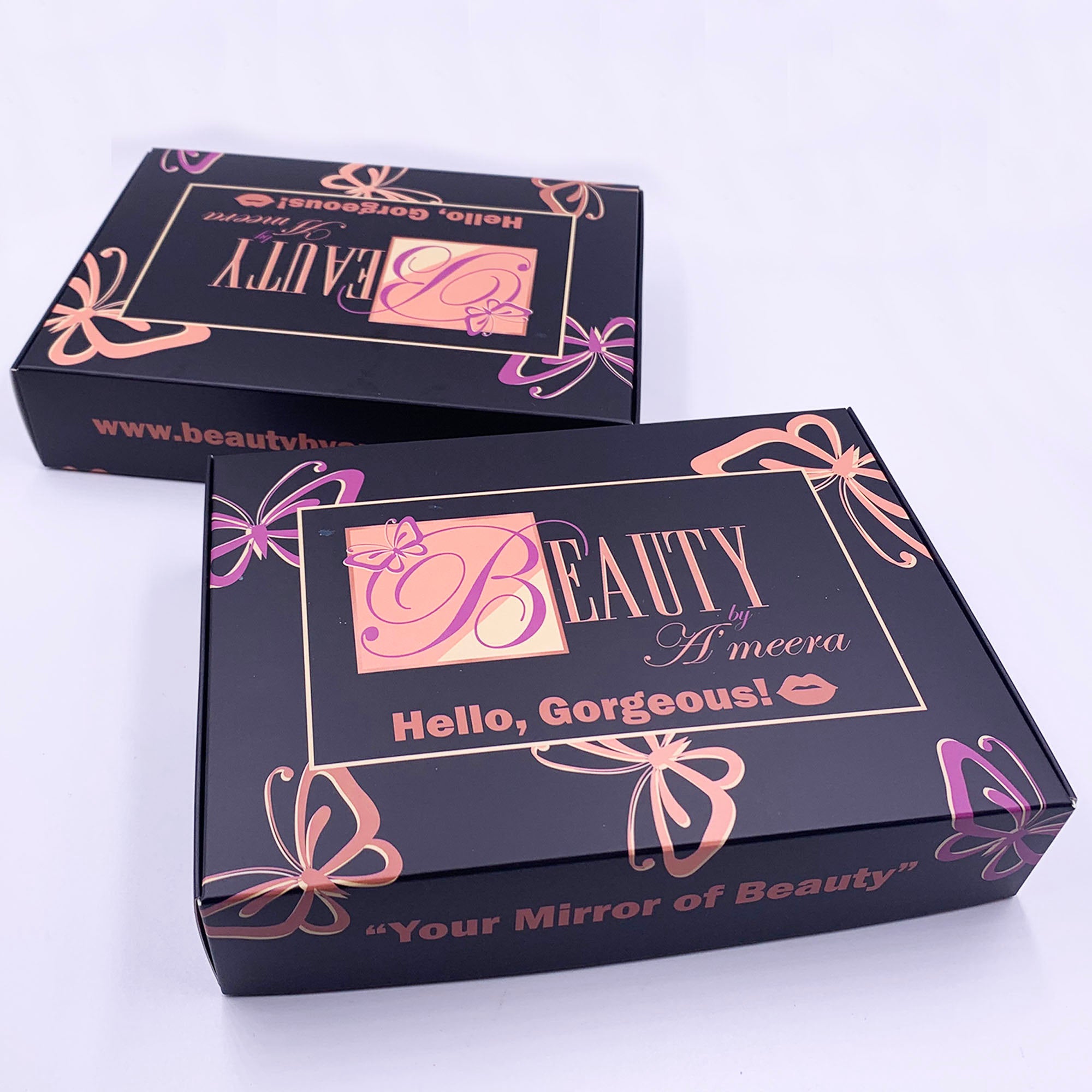 Two black boxes with pink and purple designs and text, one slightly behind the other, on a white surface.