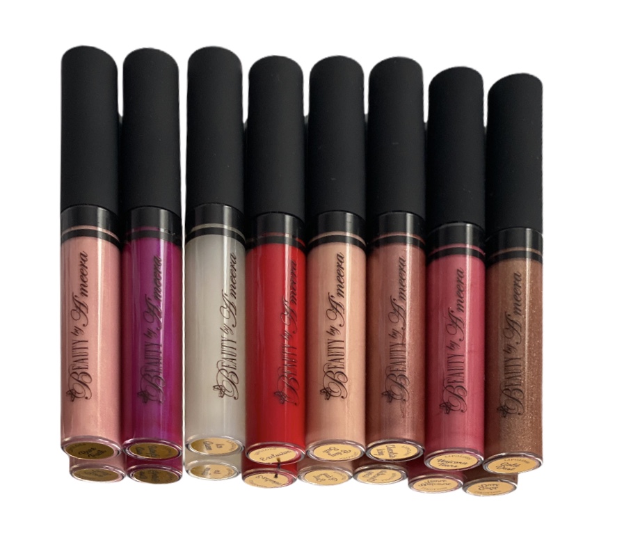 Eight lip gloss tubes with black caps arranged horizontally, showing various shades from pink to brown, on a white background.