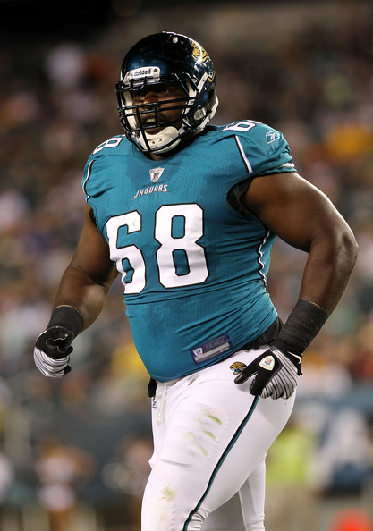 Football player in teal jersey with number 58, wearing helmet and gloves, on field during game