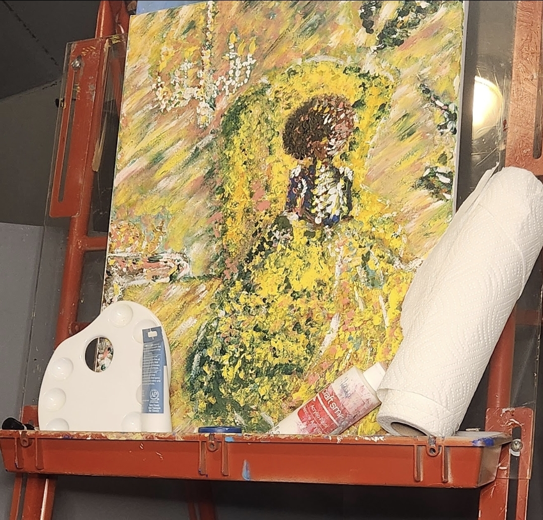 Painting of a woman in a yellow dress with a floral background, on an easel with art supplies nearby.
