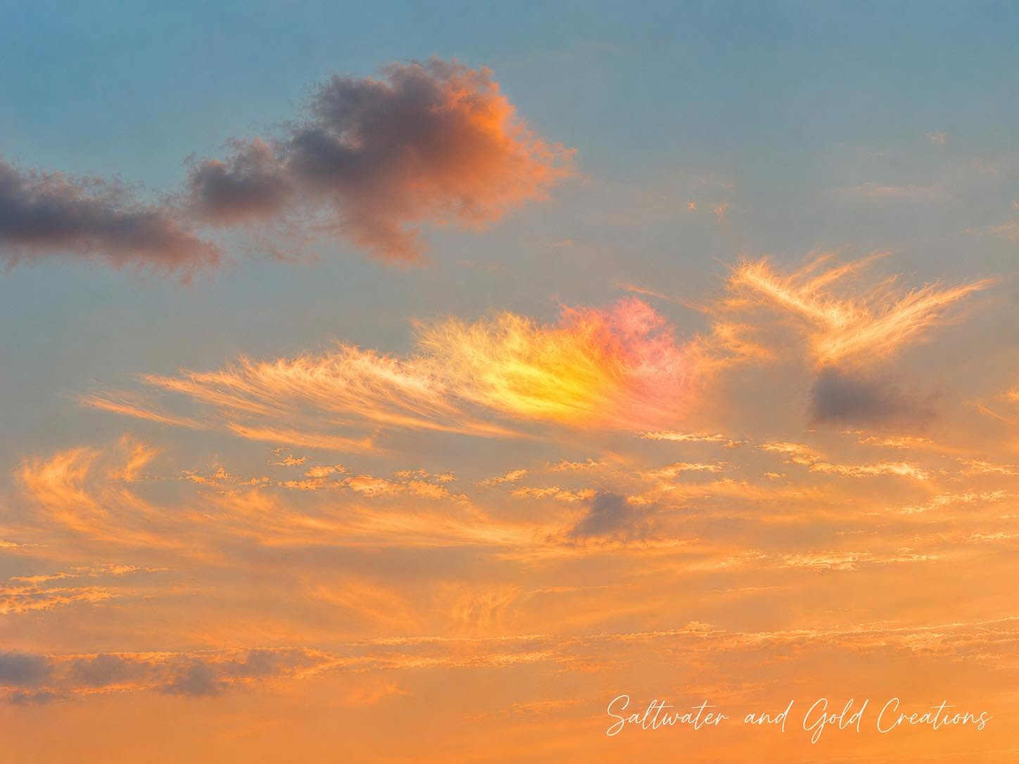 Colorful sunset sky with orange, pink, and blue clouds, and a signature in the bottom right corner.