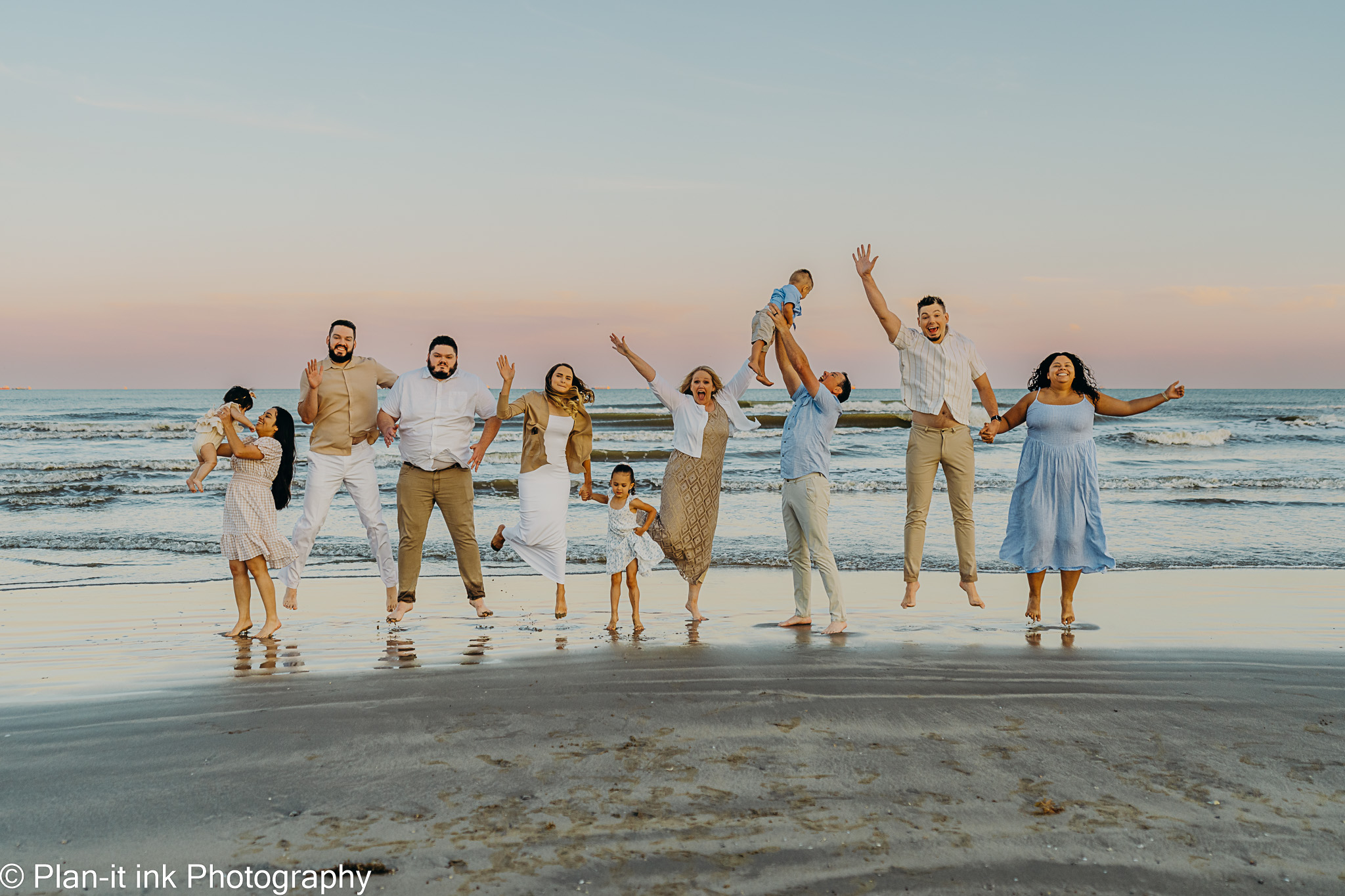 Group of people holding hands and playing on the beach during sunset, with the ocean in the background.