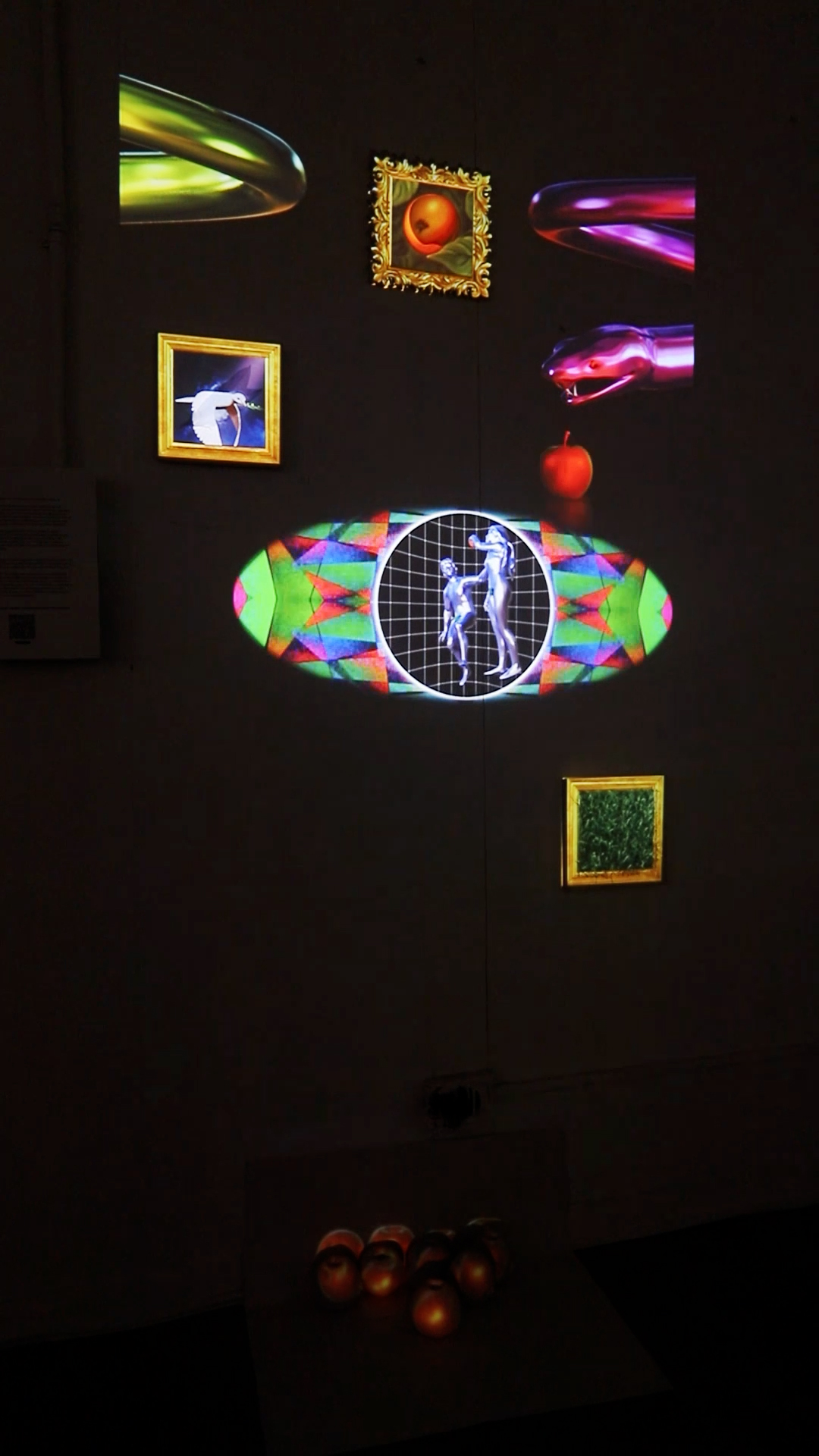 Projection of colorful images and patterns on a dark wall, including a globe, framed pictures, and abstract shapes.
