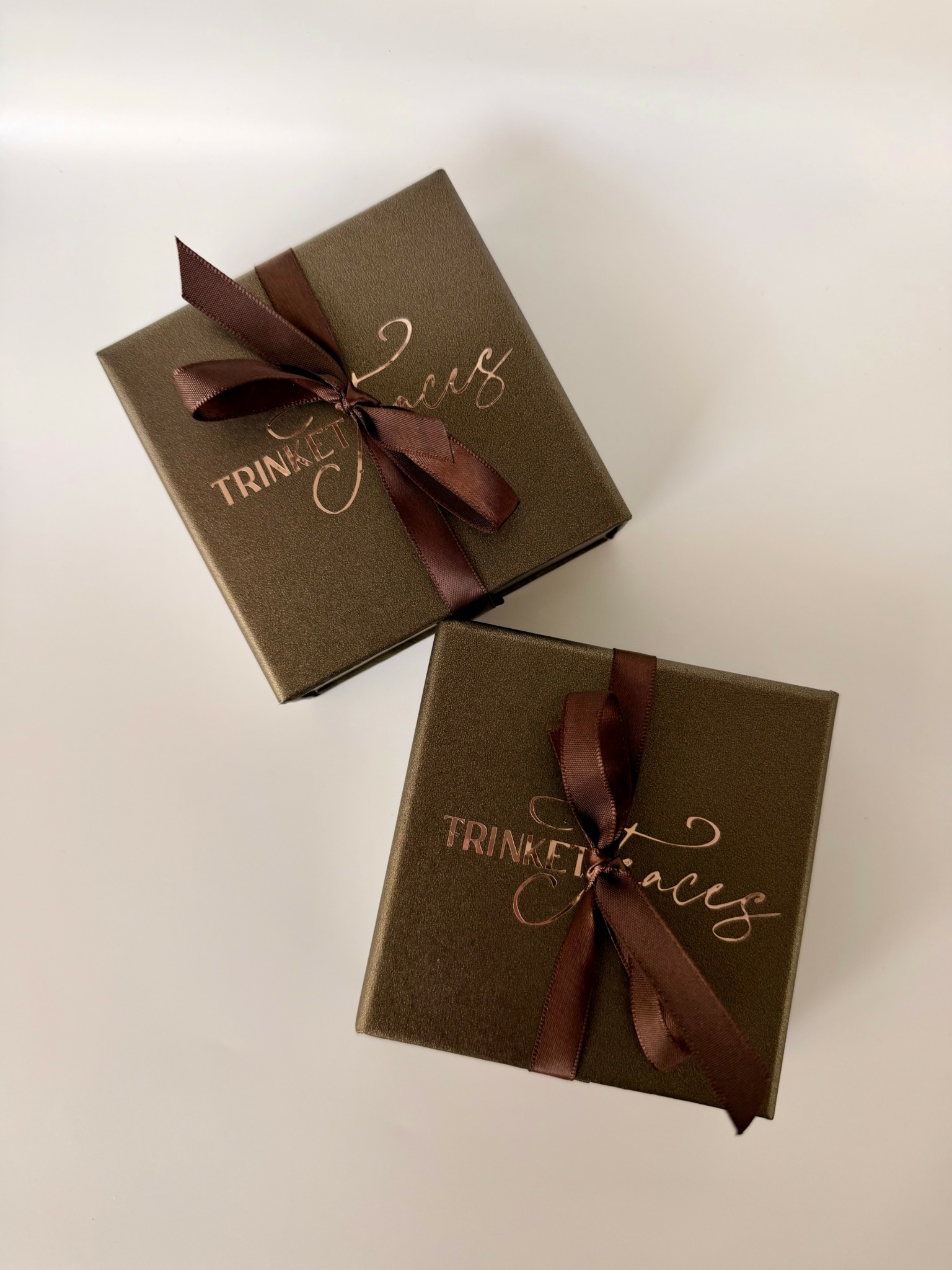 Two brown gift boxes with ribbons, one slightly above the other, on a white background.
