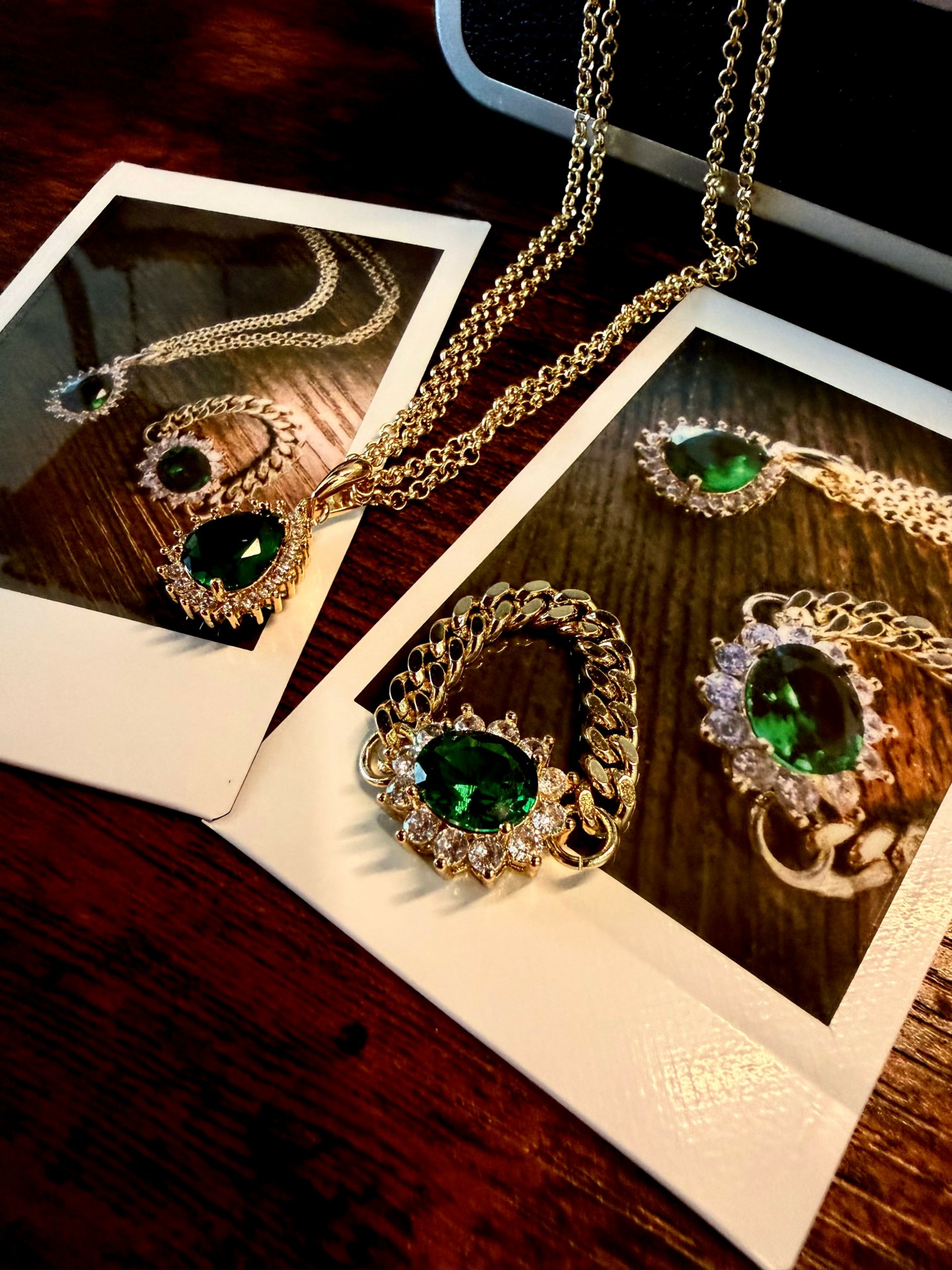 Jewelry including necklaces, rings, and earrings with green gemstones and diamonds on wooden surfaces, photographed with Polaroid-style frames.
