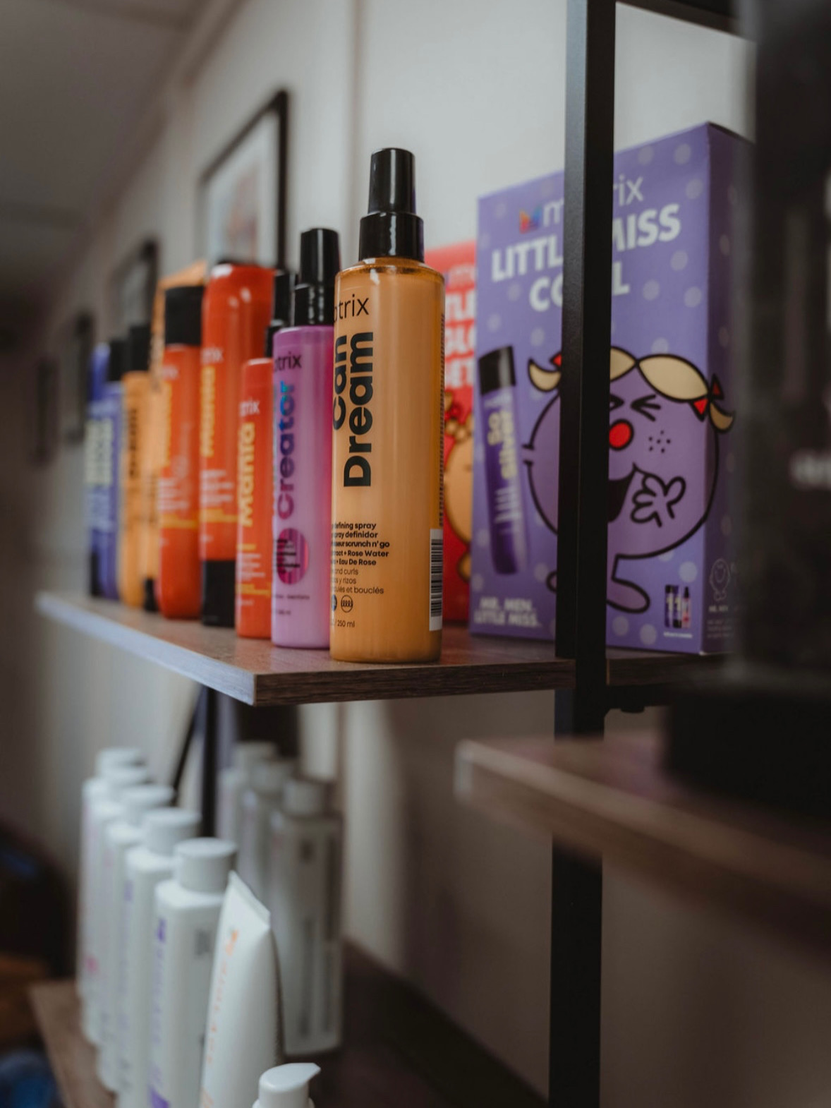 Shelf with skincare and beauty products, including spray bottles and boxed items, in a store or display setting.