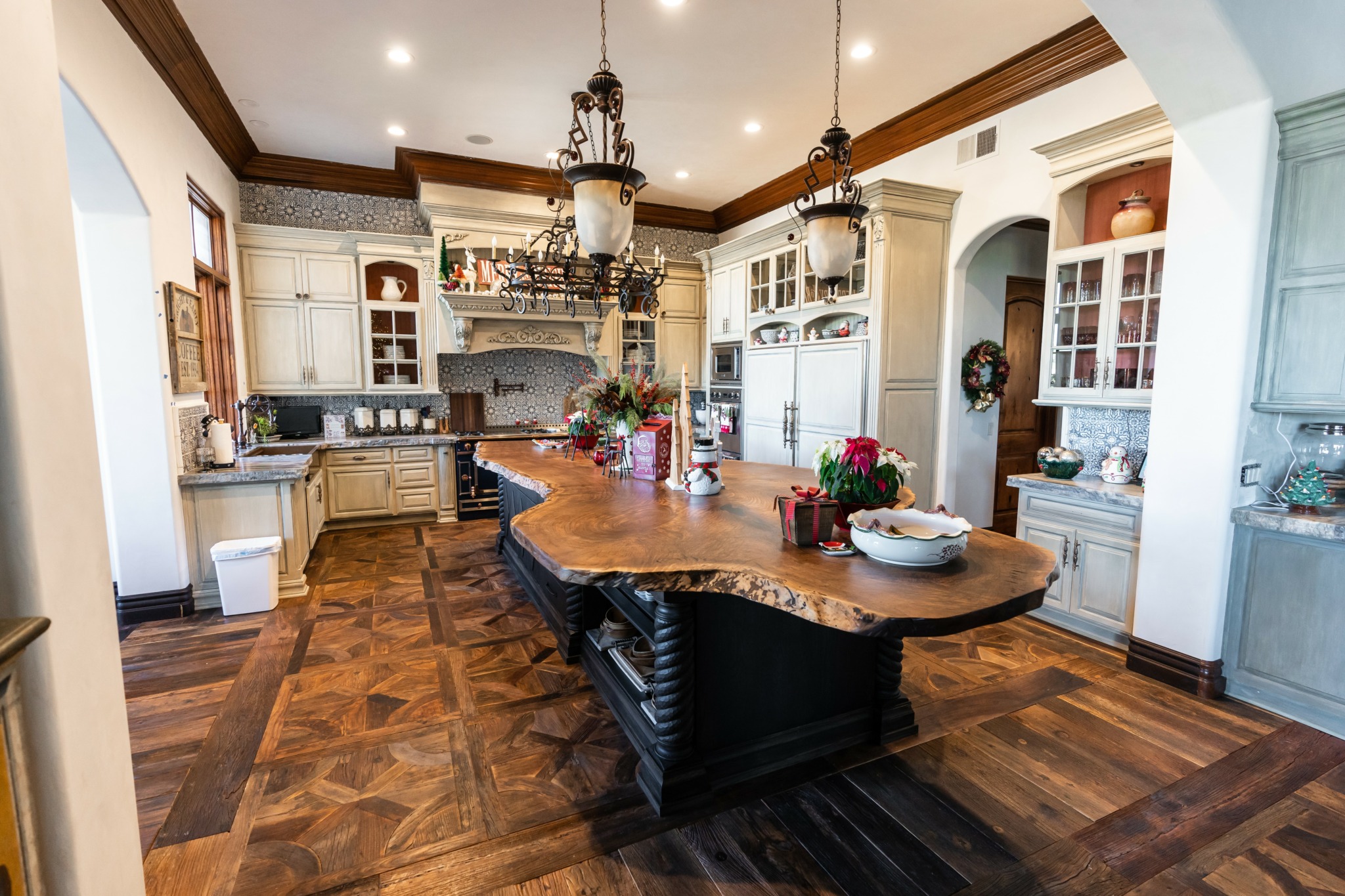 Spacious kitchen with wooden cabinets, central island, and hardwood flooring, decorated with flowers and hanging lights.