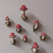 Small decorative mushrooms with red caps and white spots attached to a wall, casting shadows.