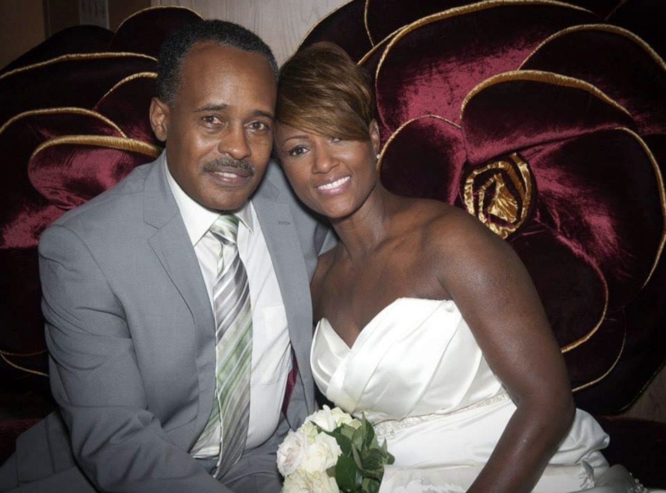 A man and woman sit close together, smiling, with velvet theater seats in the background.