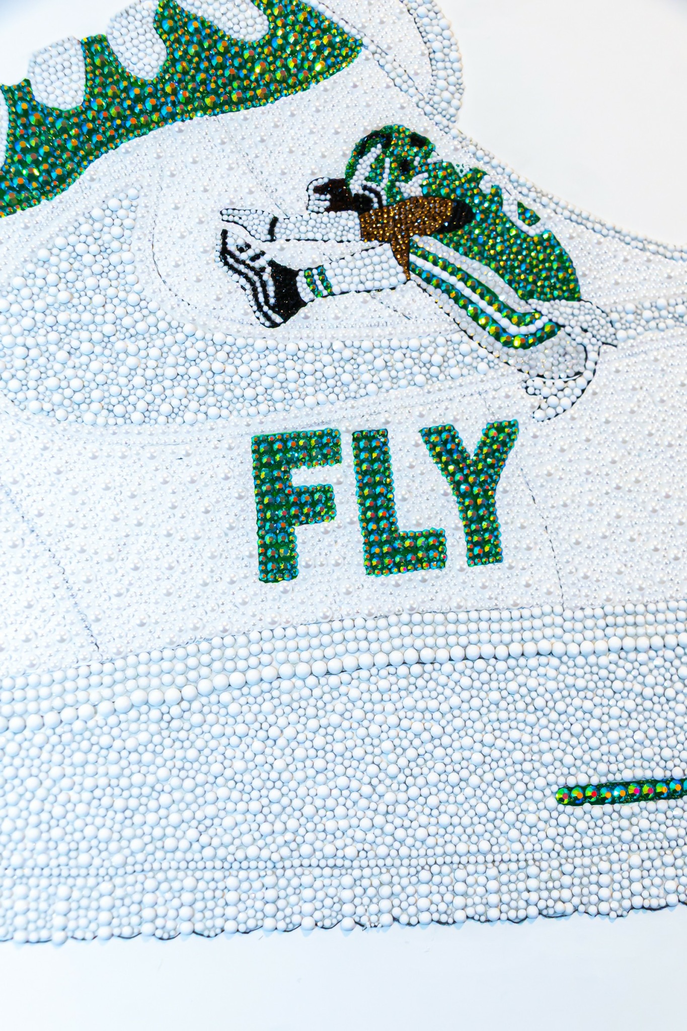 Close-up of a textured fabric with the word 'FLY' and a cartoon character with wings, green and black details.