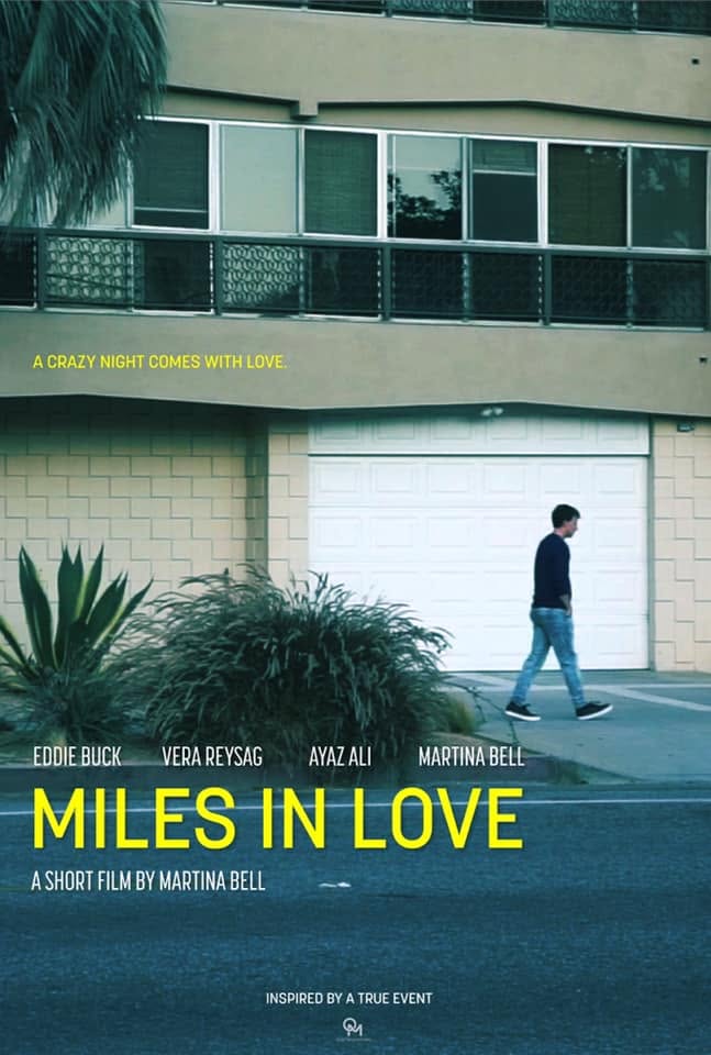 Person walking past a building with large windows and a white garage door, greenery in foreground, movie title and credits overlayed.