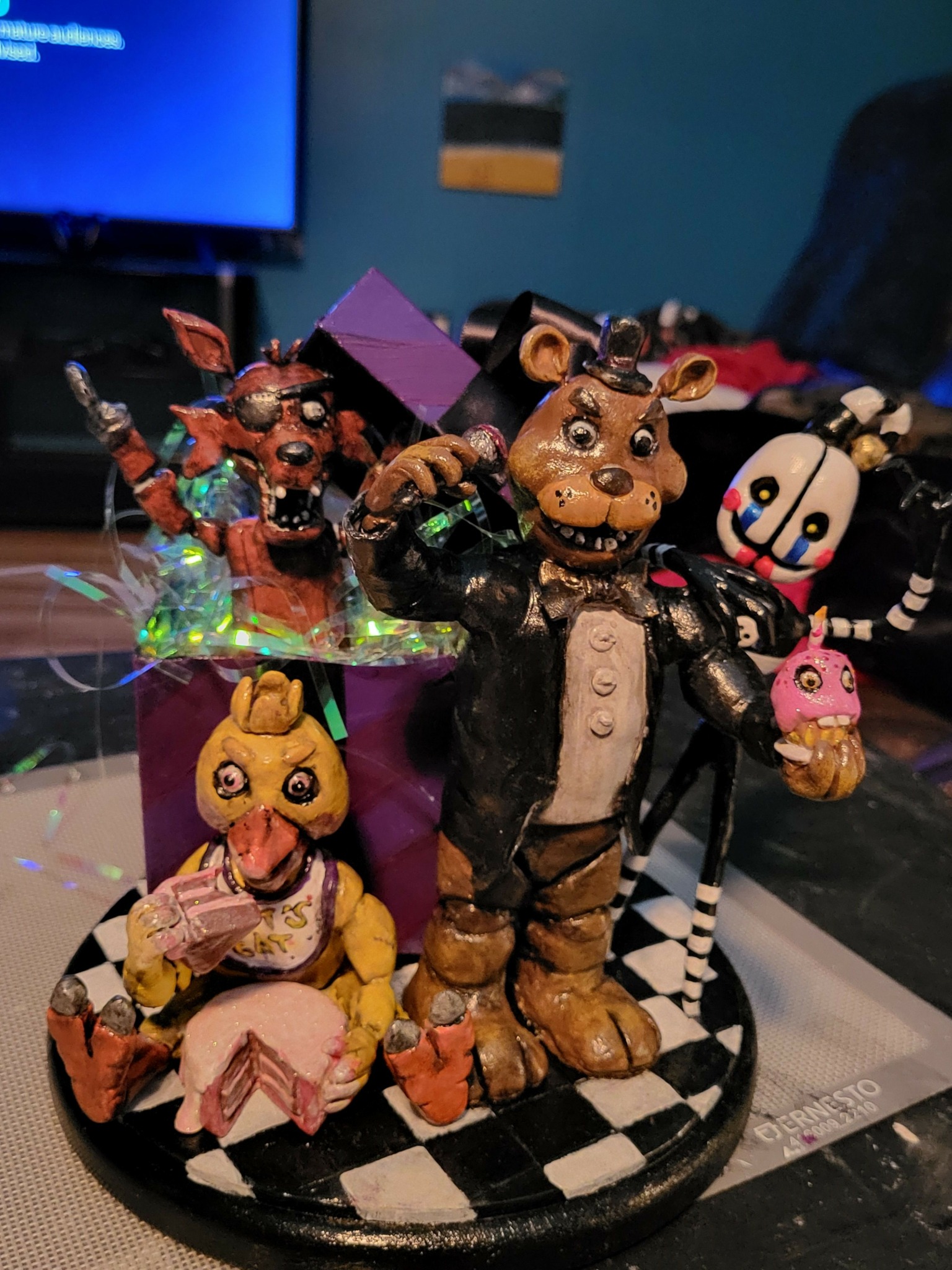 Collection of colorful toy characters on a circular base, including animals and animated figures, with a blue background.