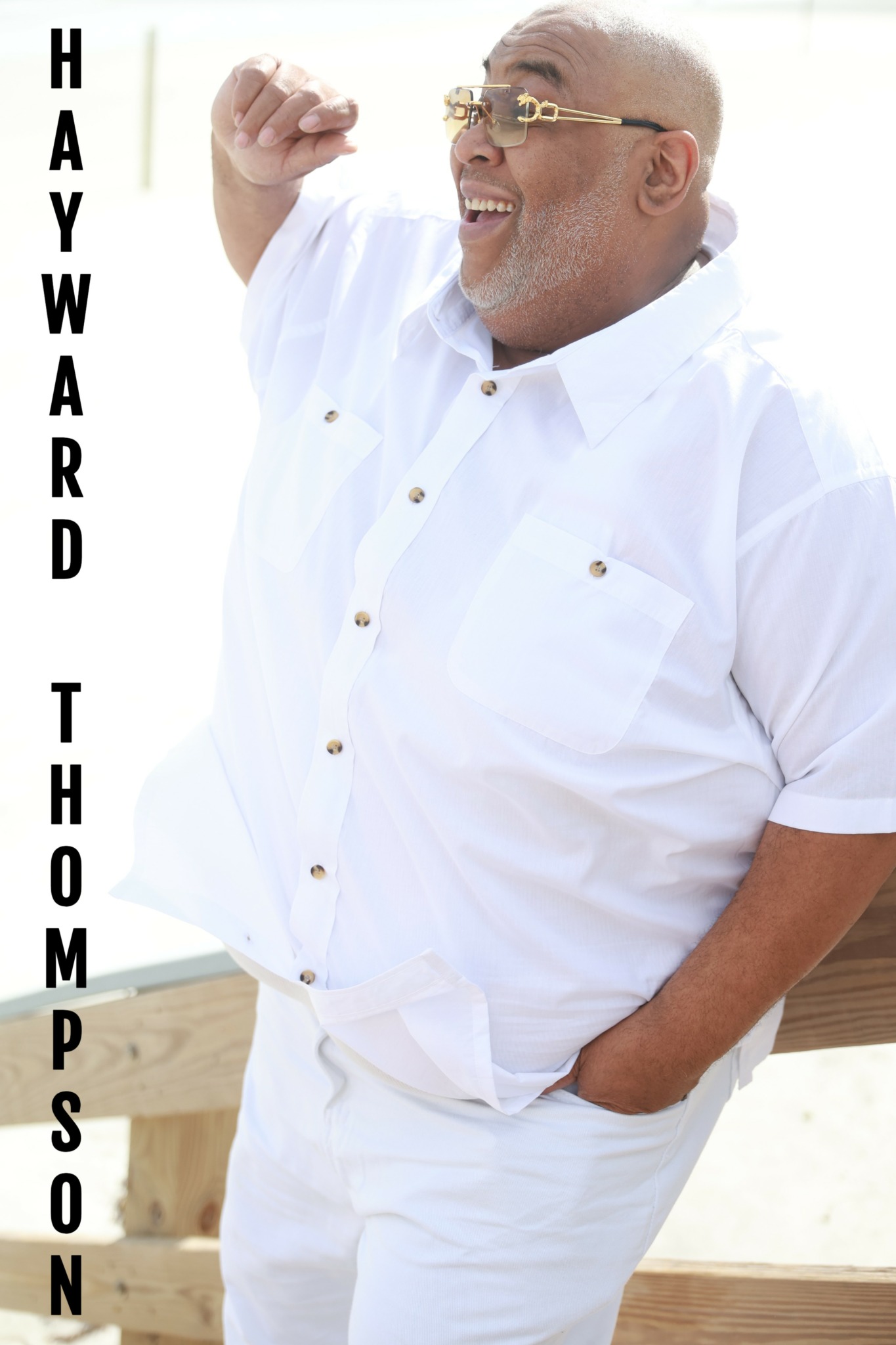 Smiling man in white shirt and glasses leaning on a wooden railing outdoors, with text 'HAYWARD THOMPSO' vertically on the left.