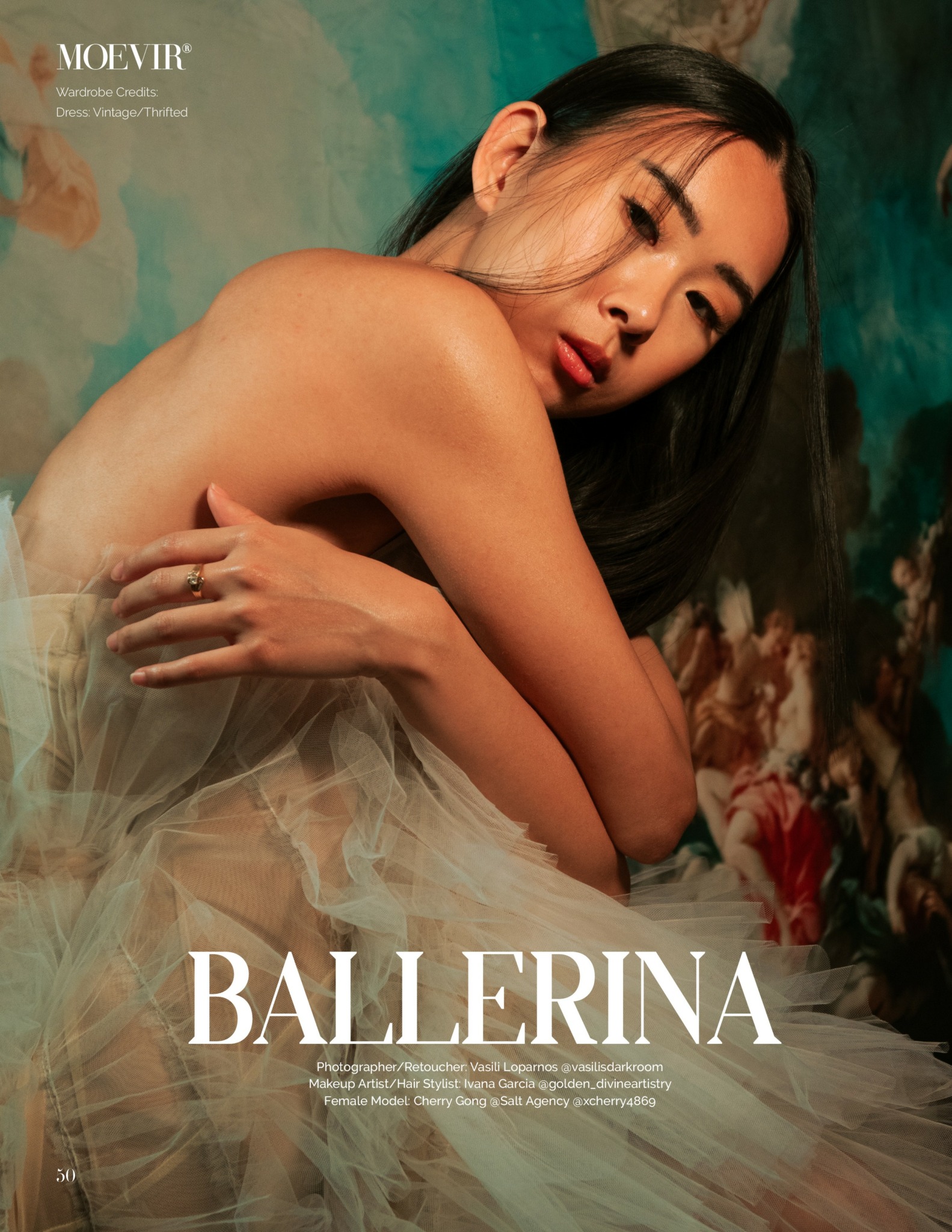 A woman with long dark hair and closed eyes, wearing a light, flowing dress, poses with her arms crossed over her chest.
