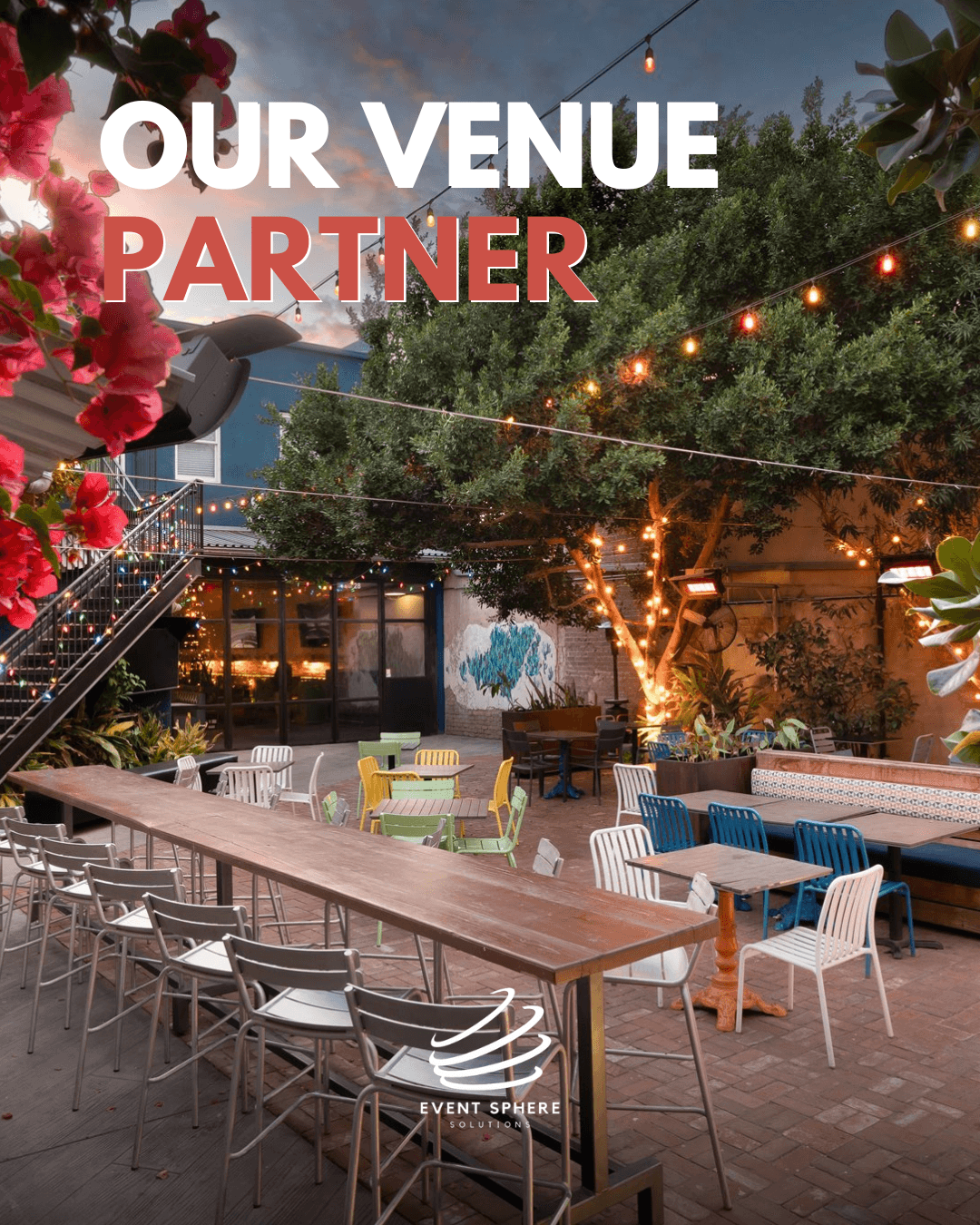 Outdoor venue with string lights, trees, and seating arrangements, including tables and chairs, under a partly cloudy sky.